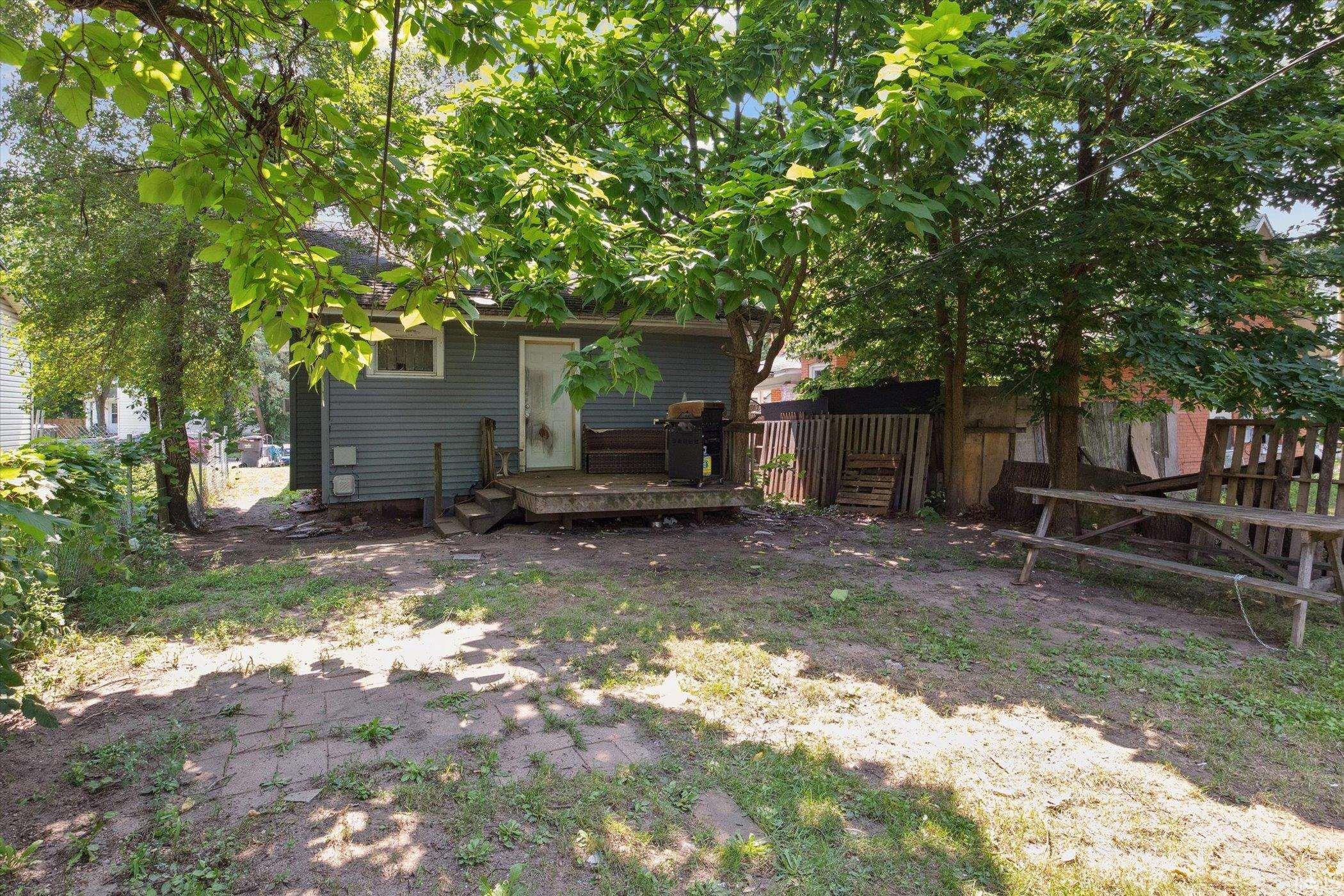 Rear exterior featuring blue siding, a wooden deck, and a fenced perimeter