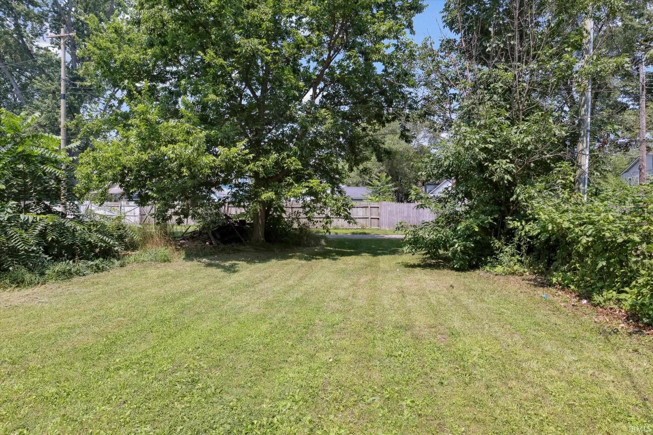 Expansive lot featuring a manicured lawn, established mature trees, and natural perimeter foliage