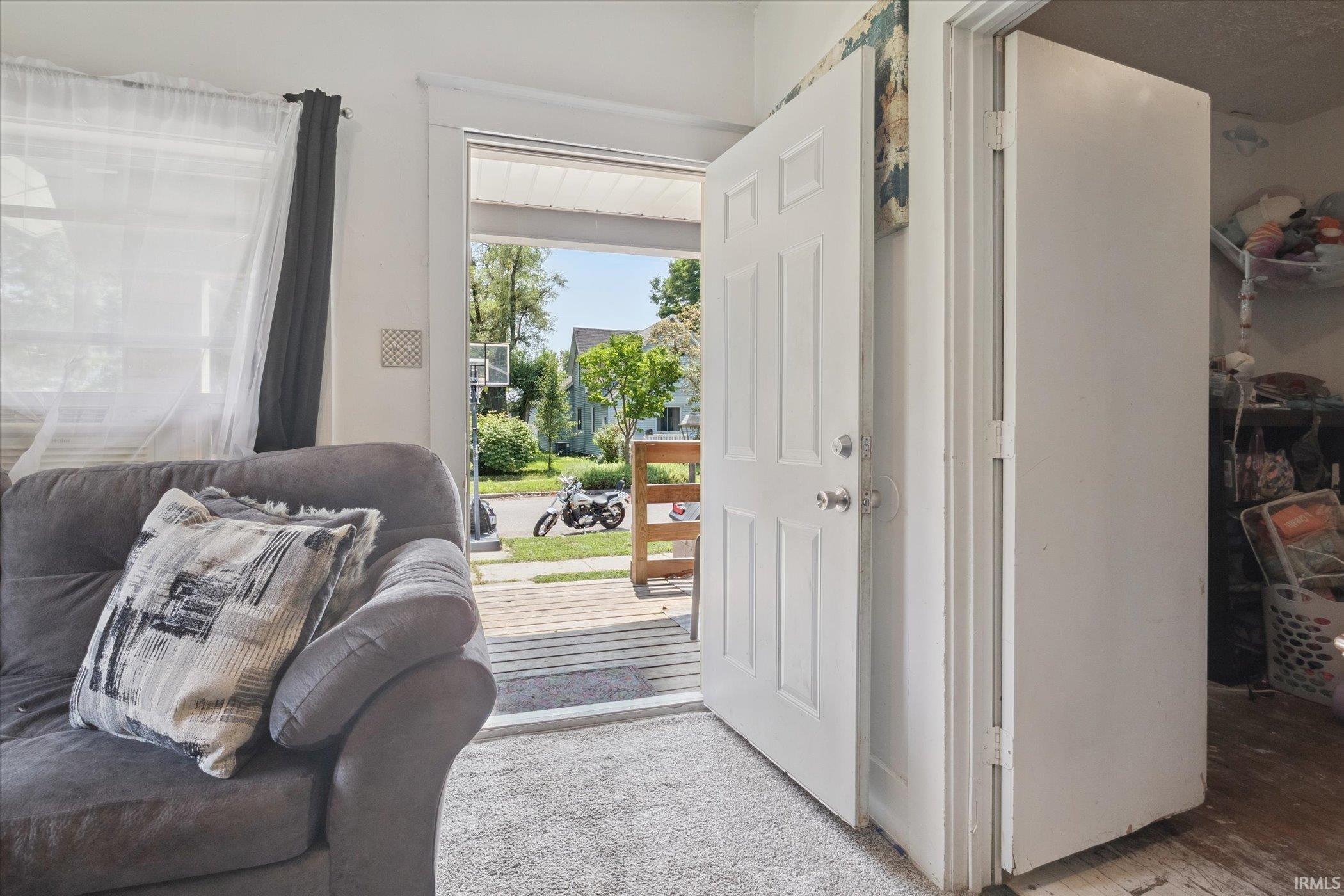 Bright interior space featuring a white paneled door and light-colored carpeting