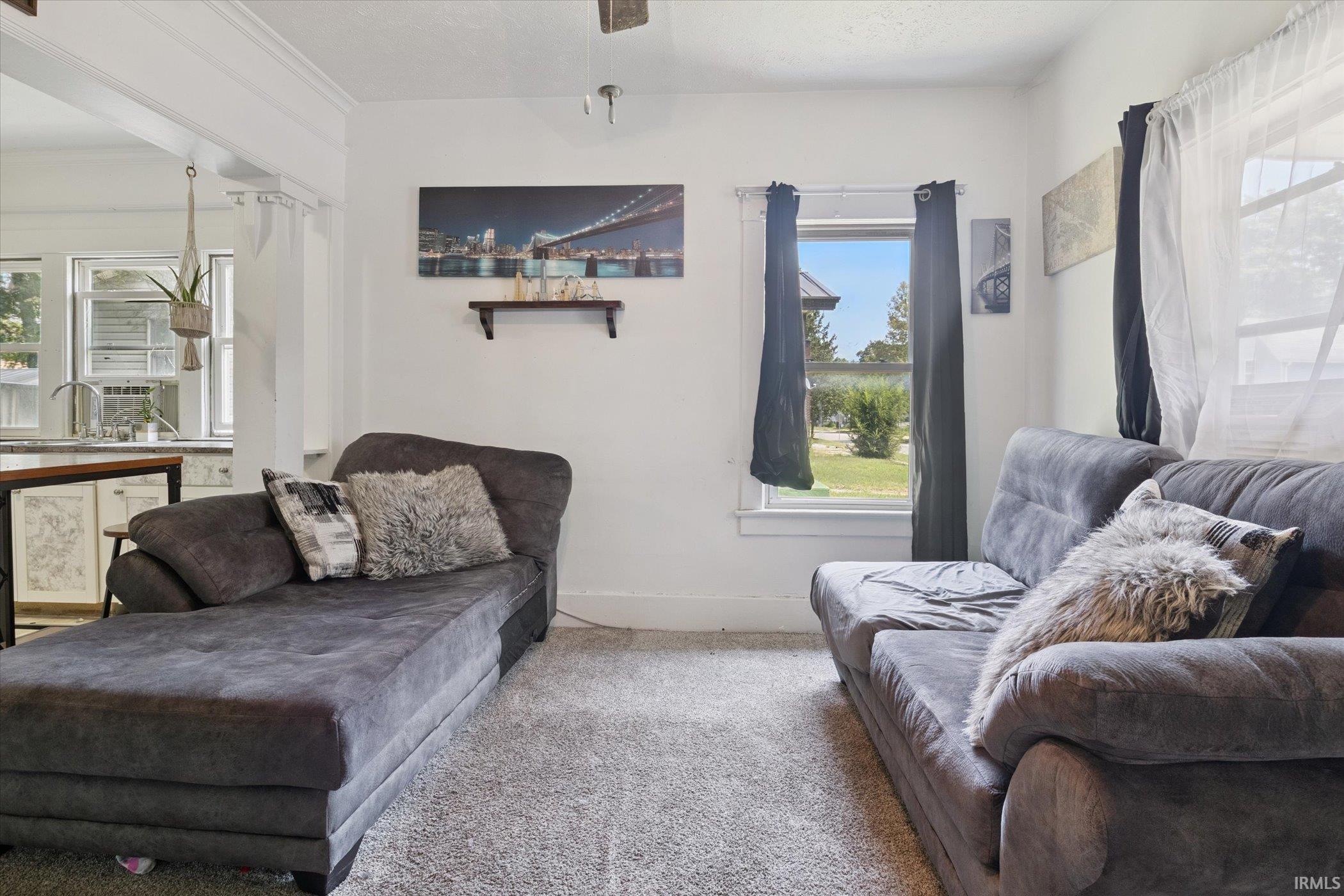 Open-concept living area featuring light-colored walls and carpet flooring