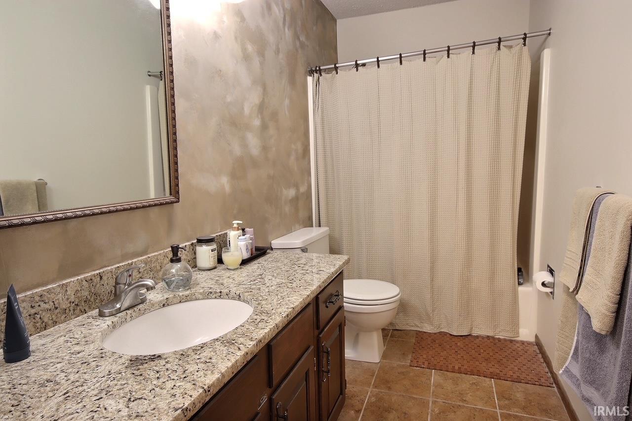 Bathroom featuring a vanity with a granite-style countertop, an undermount sink, and a framed mirror