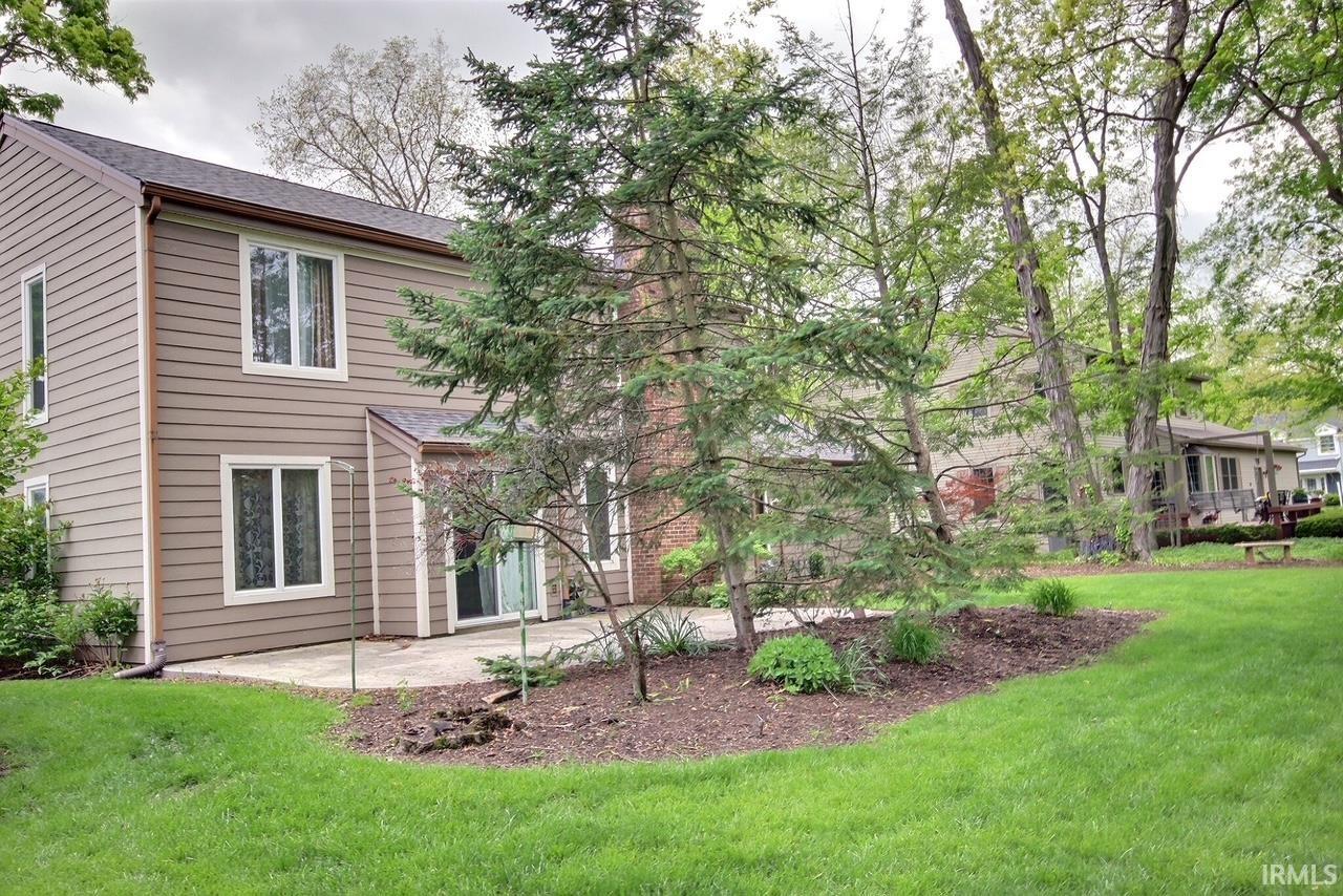 Rear exterior featuring neutral-toned siding, white-framed windows, and a brown roof
