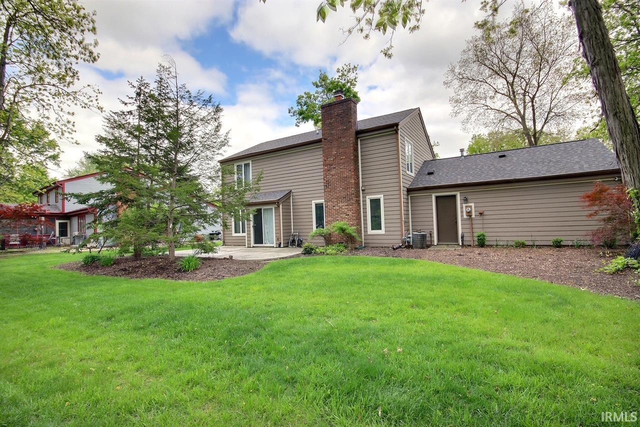 Expansive backyard featuring a manicured lawn, established landscaping, and a paver patio