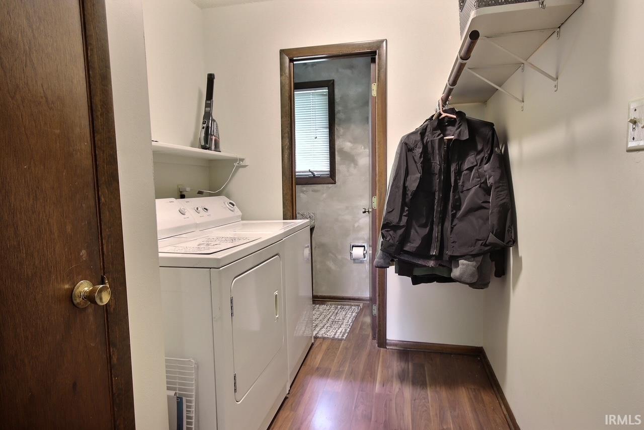 Dedicated laundry area featuring a white top-load washing machine, a white dryer, and wood-finish flooring