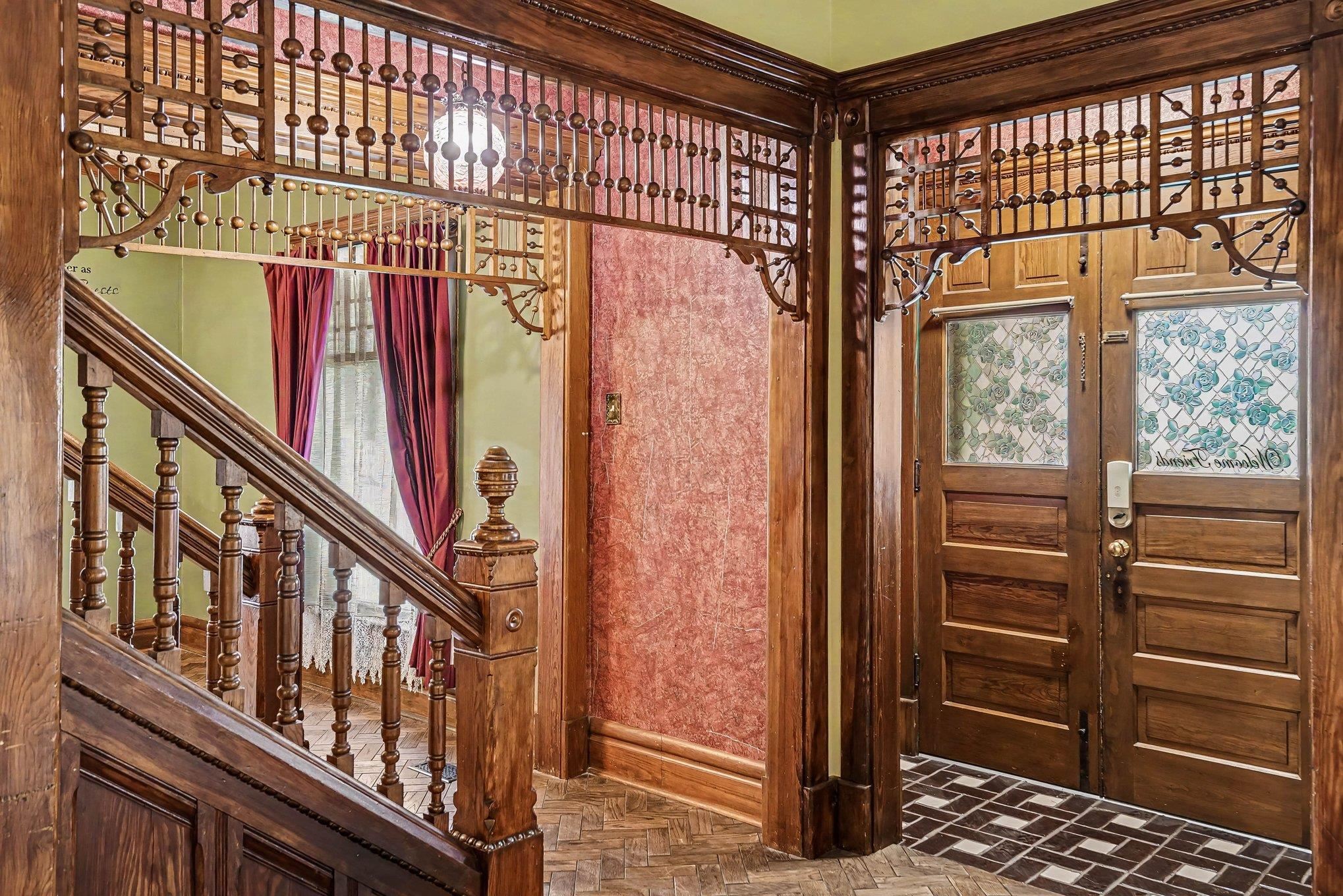 Ornate wood craftsmanship defining a grand entryway with a staircase and decorative screen details