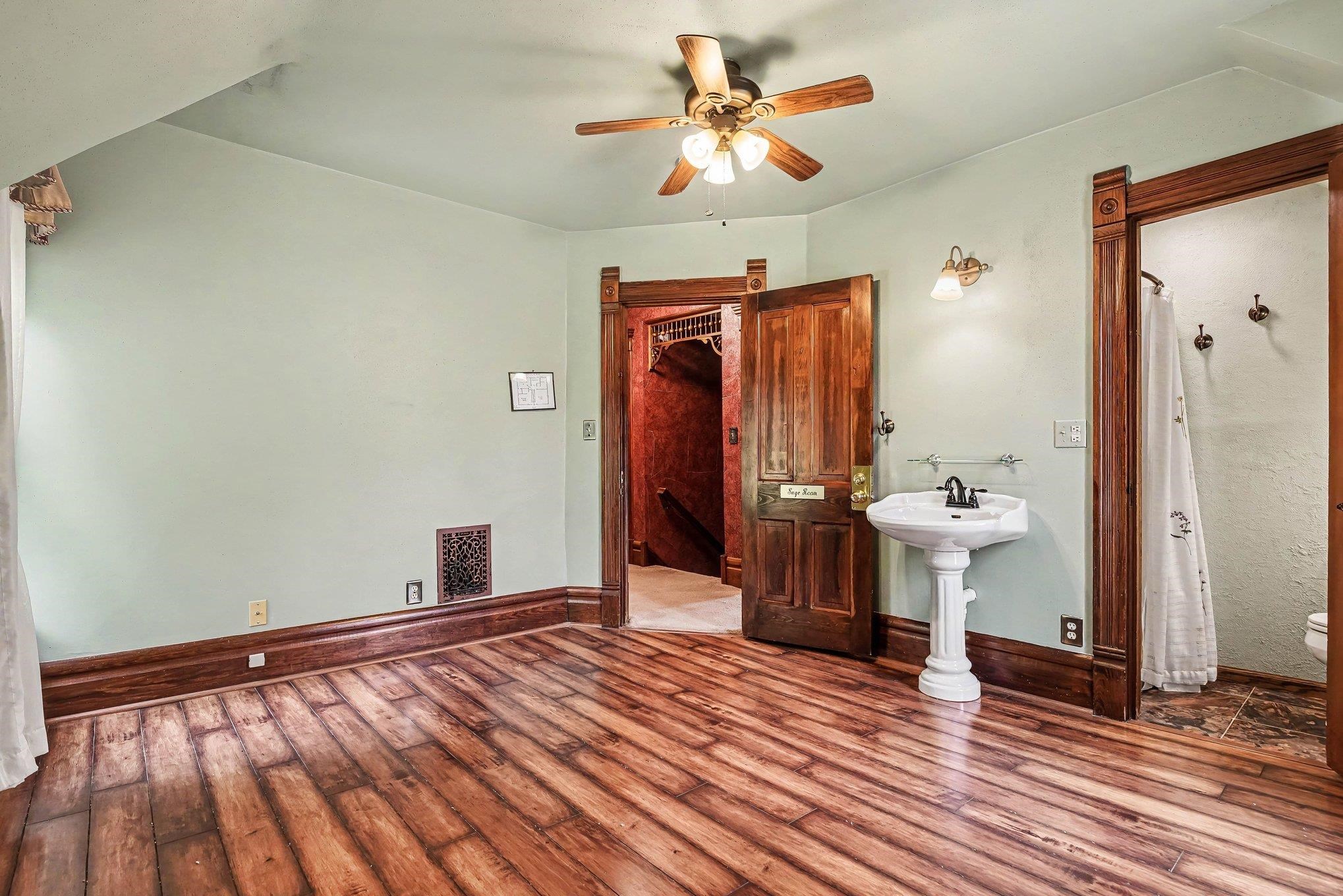 Room featuring wood-finish flooring, light green walls, and rich wood trim