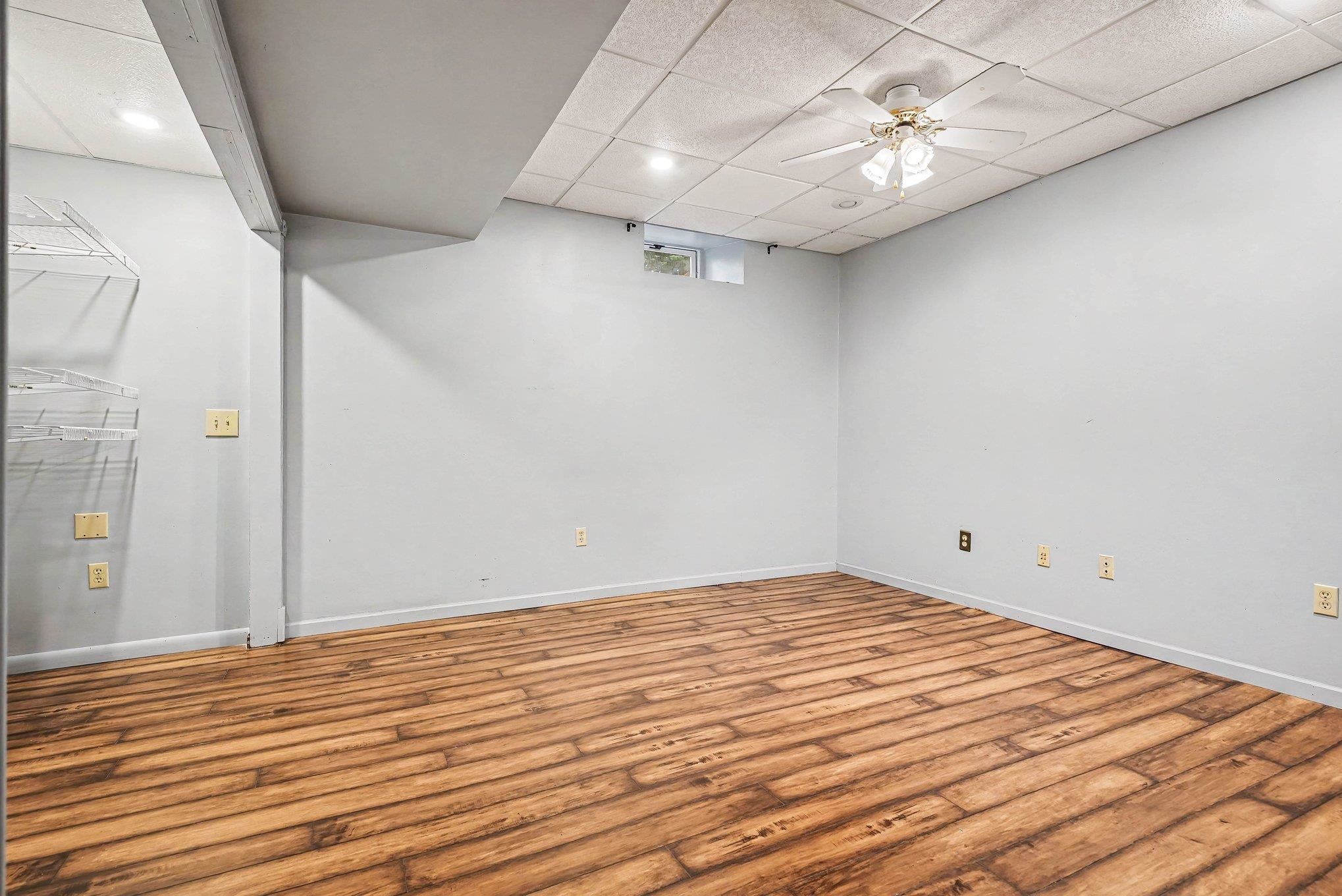 Finished room featuring wood-finish flooring, light grey walls, and a drop ceiling with recessed lighting