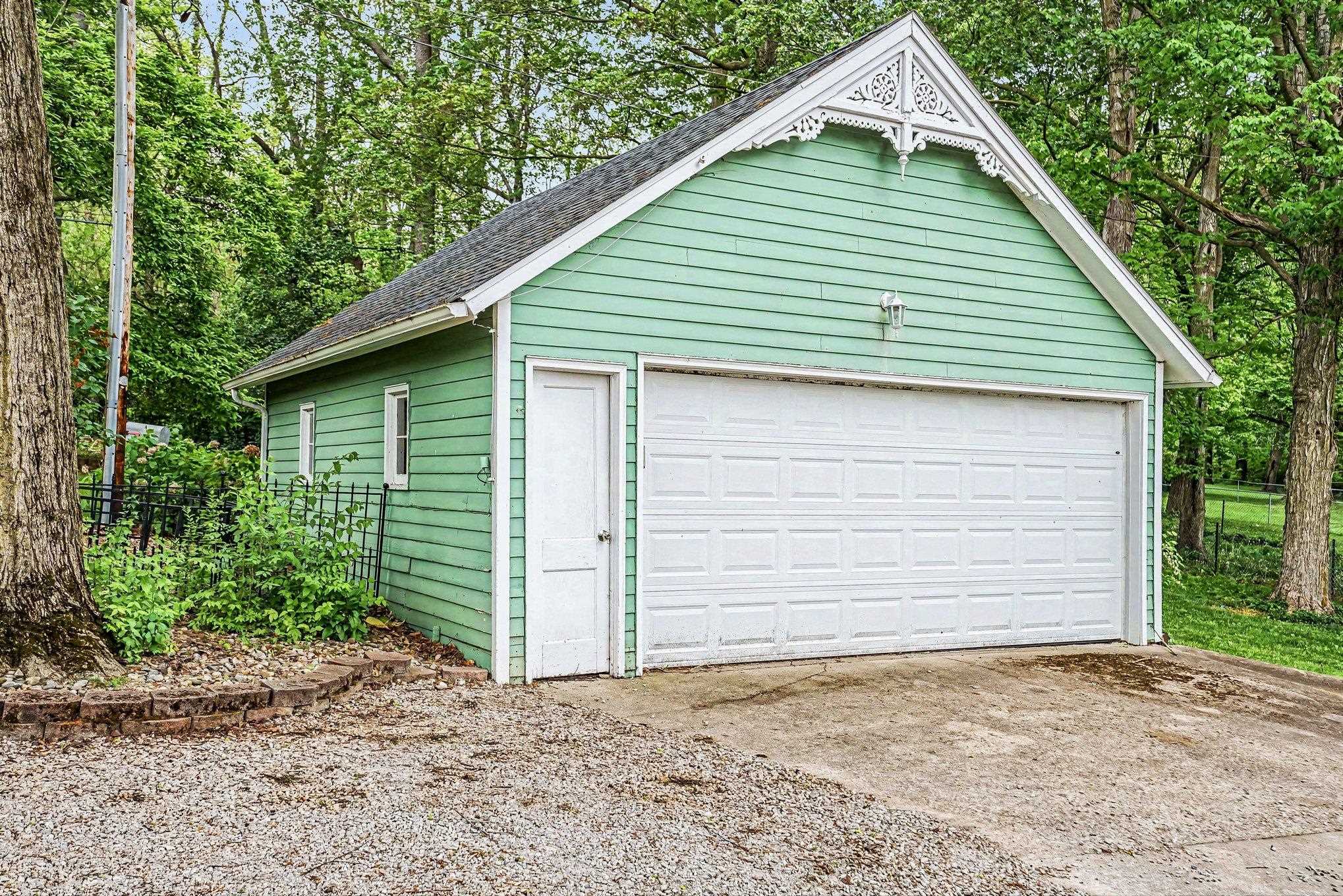 Detached garage featuring mint green horizontal siding, a white paneled garage door, and a single white entry door