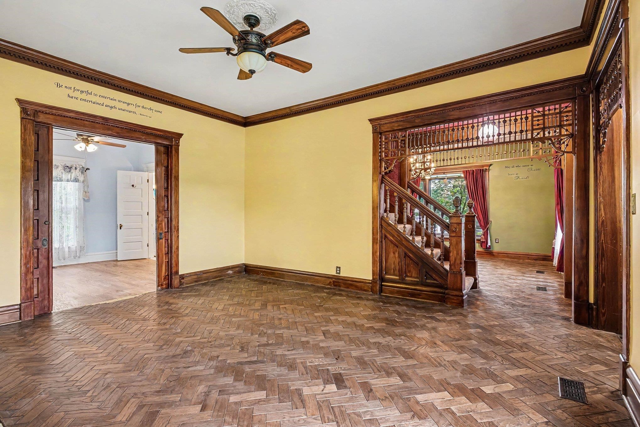 Wood-finish herringbone flooring in a room featuring yellow walls and dark wood trim