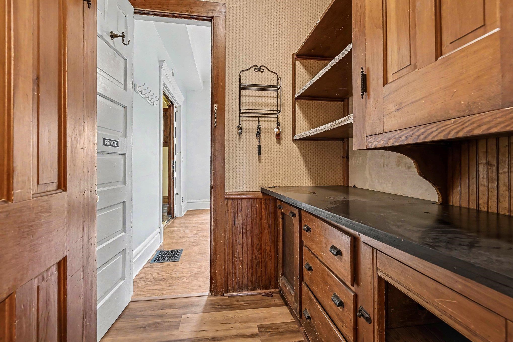 Built-in wood cabinetry with black hardware, black countertops, and open shelving