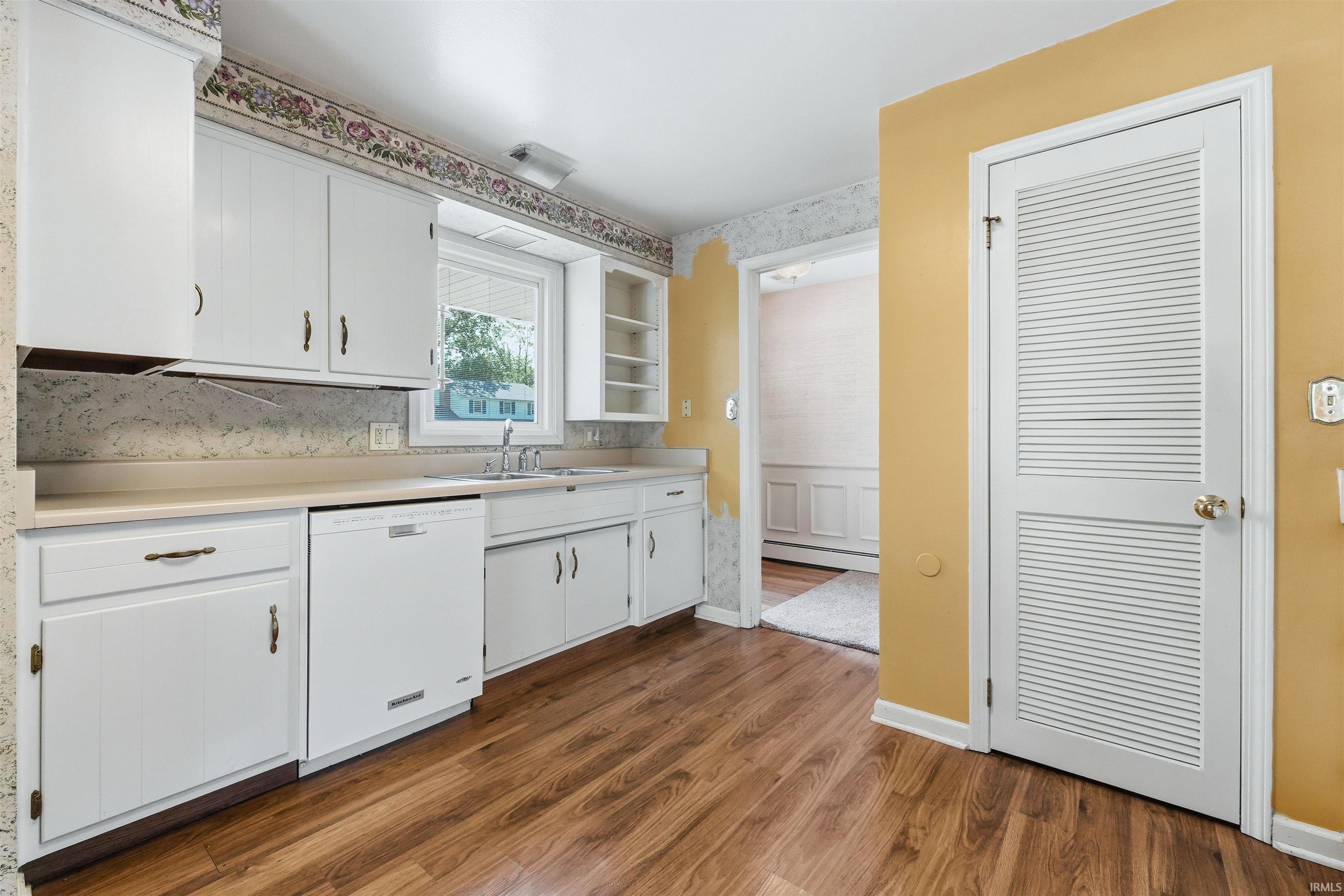 Kitchen featuring wood-finish flooring and white cabinetry