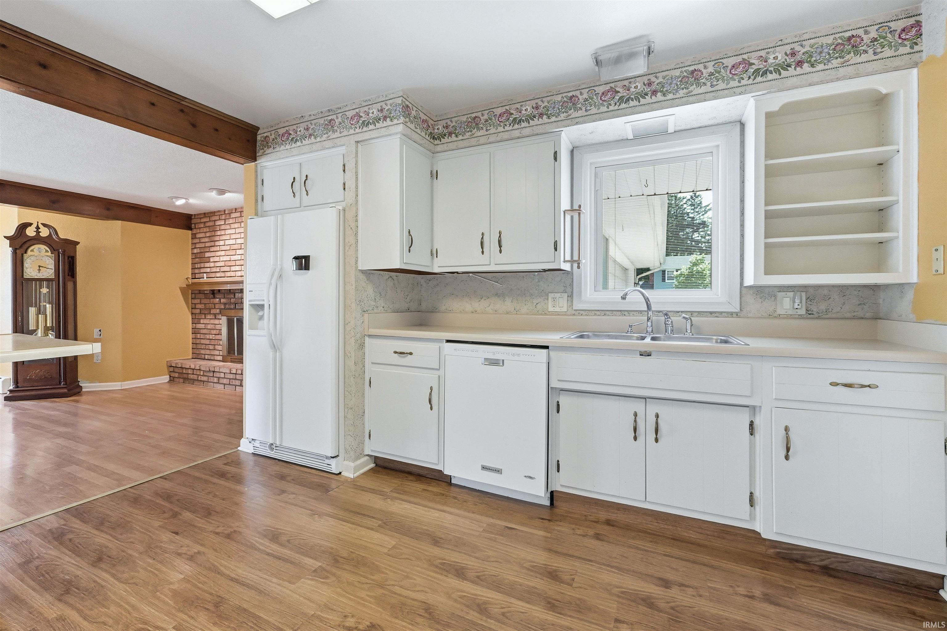Kitchen featuring wood-finish flooring, white cabinetry, integrated appliances, and a double basin sink
