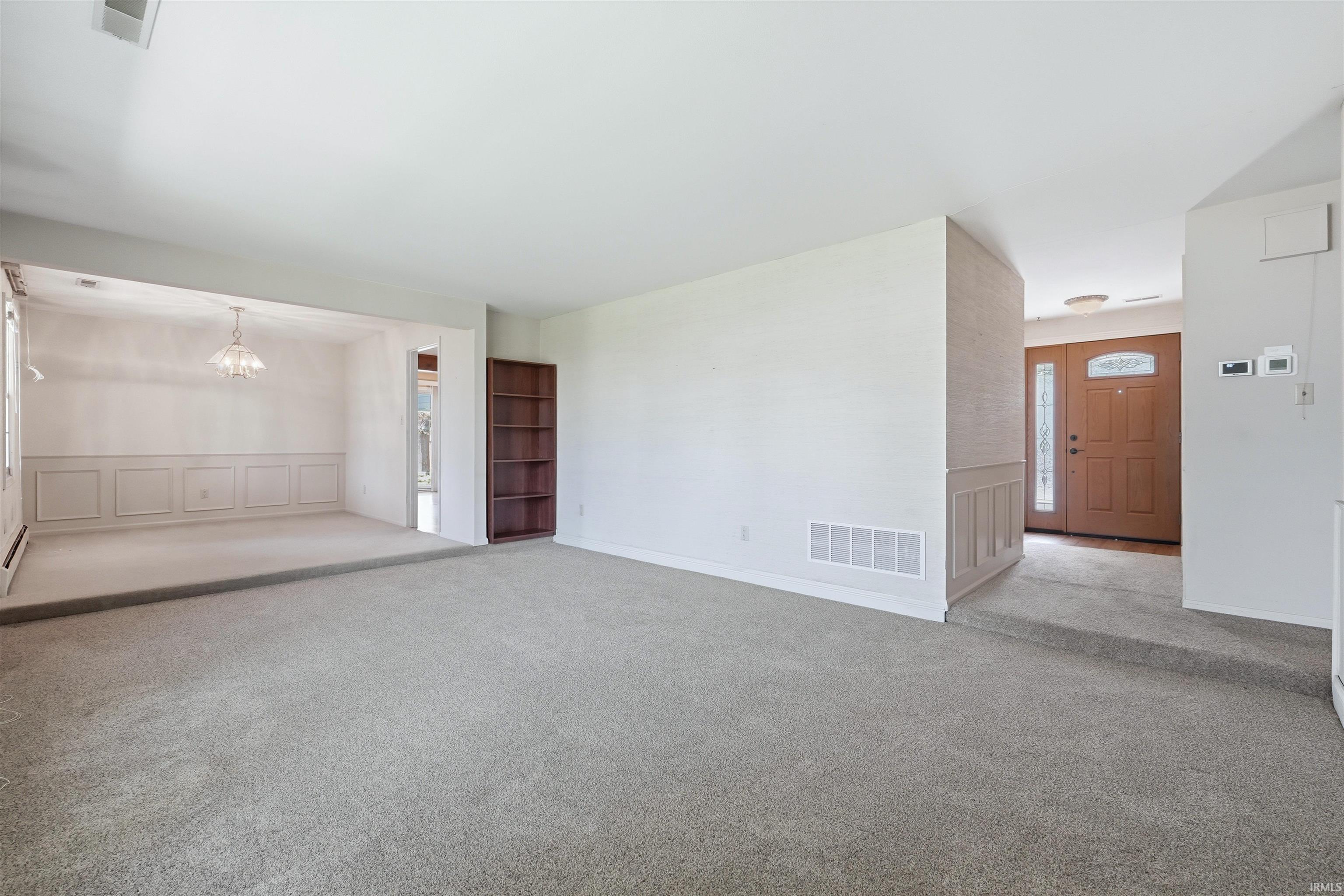 Expansive carpeted living area with a built-in dark wood shelving unit