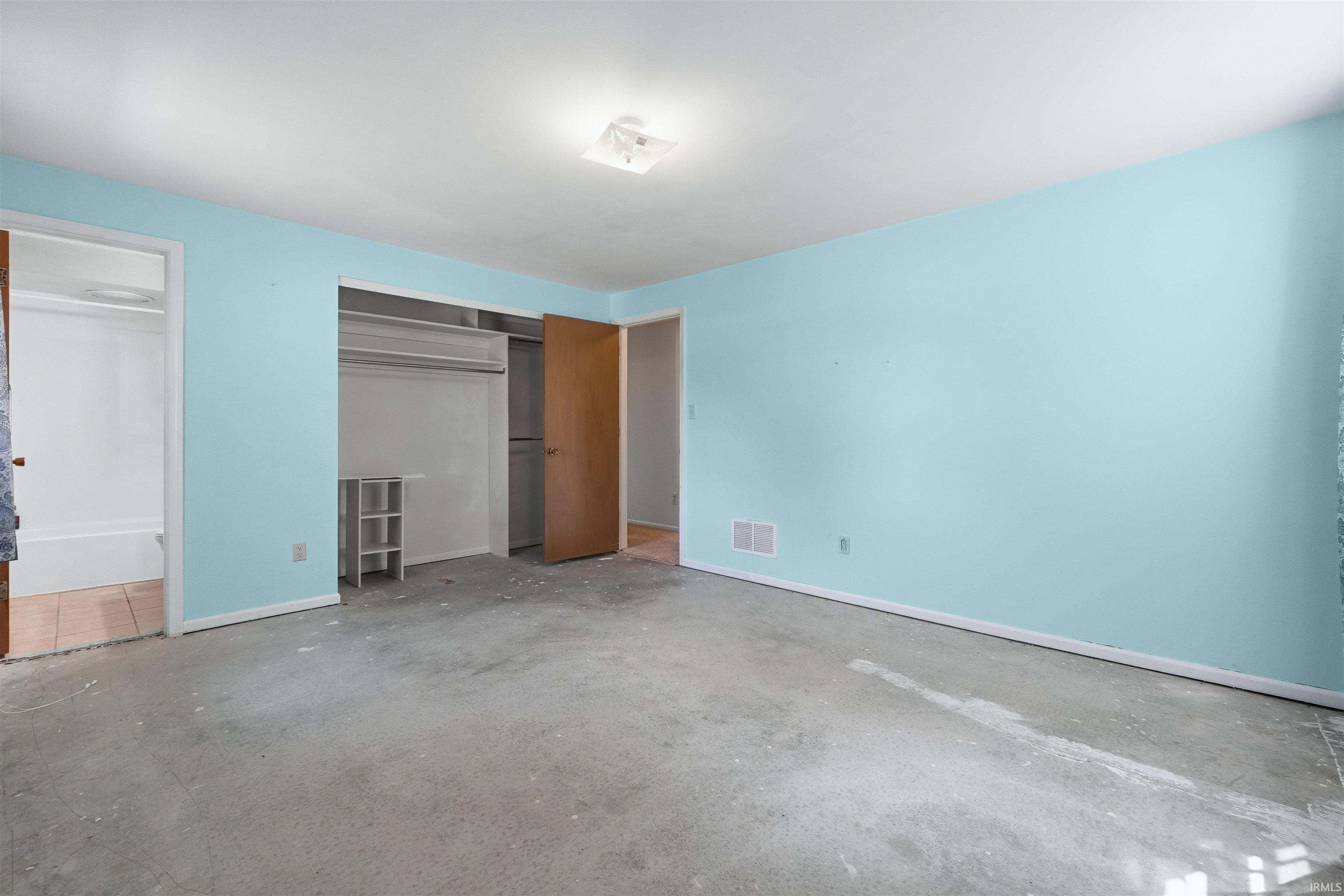 Spacious room featuring light blue walls and a concrete floor