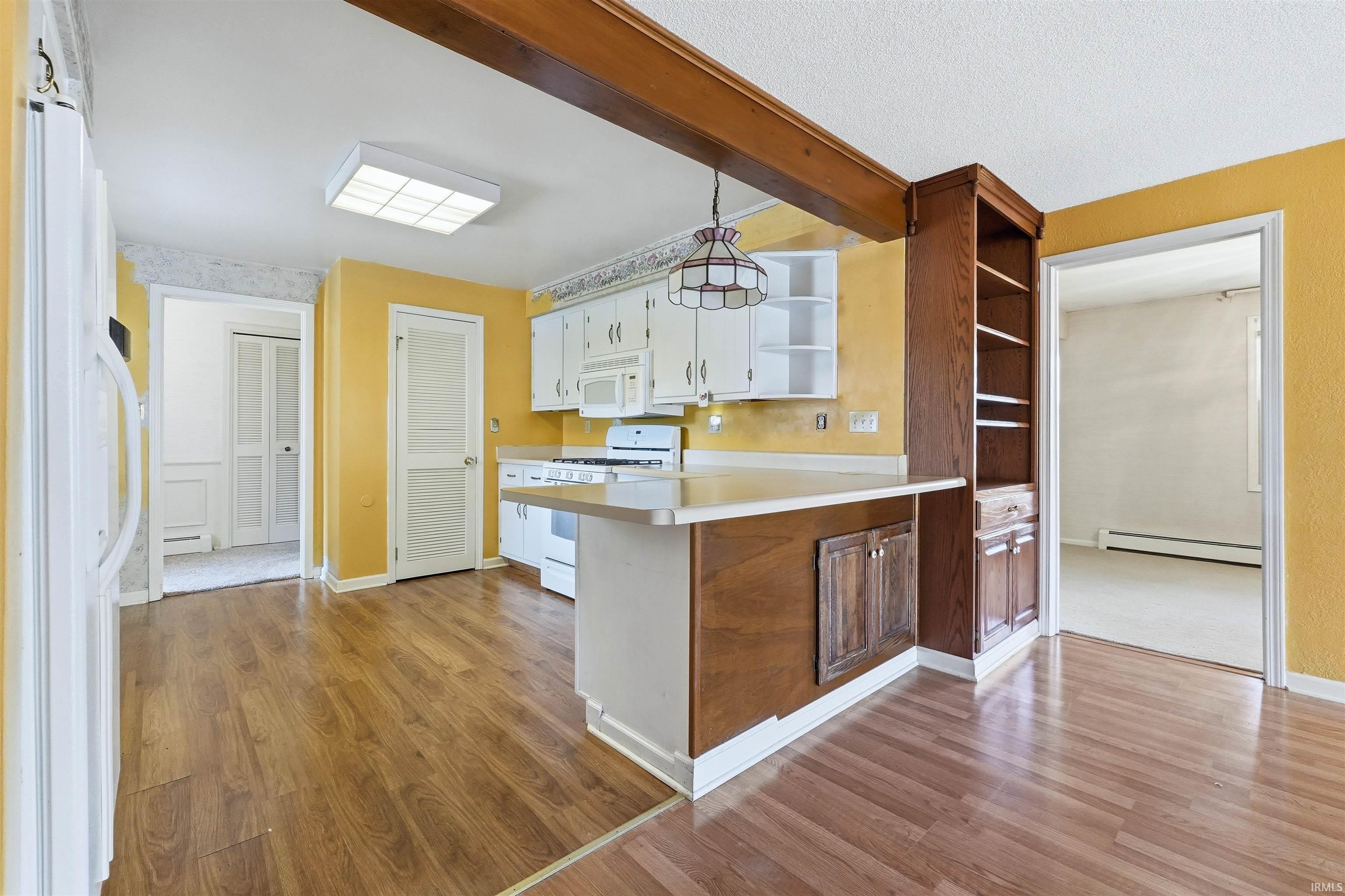 Kitchen featuring wood-finish flooring, white cabinetry, and a central island with a breakfast bar