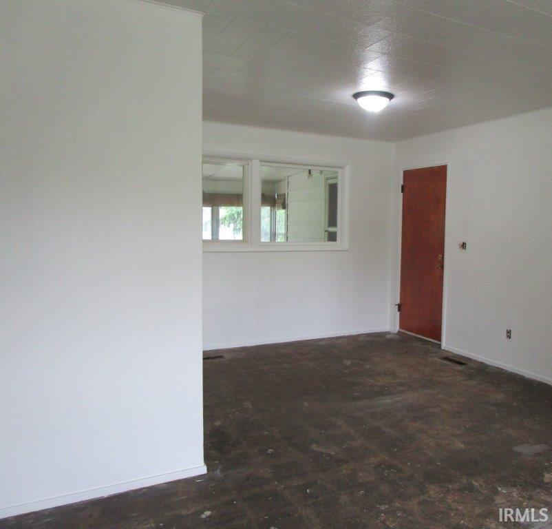 Open-concept room featuring white painted walls and ceiling with a semi-flush mount light fixture