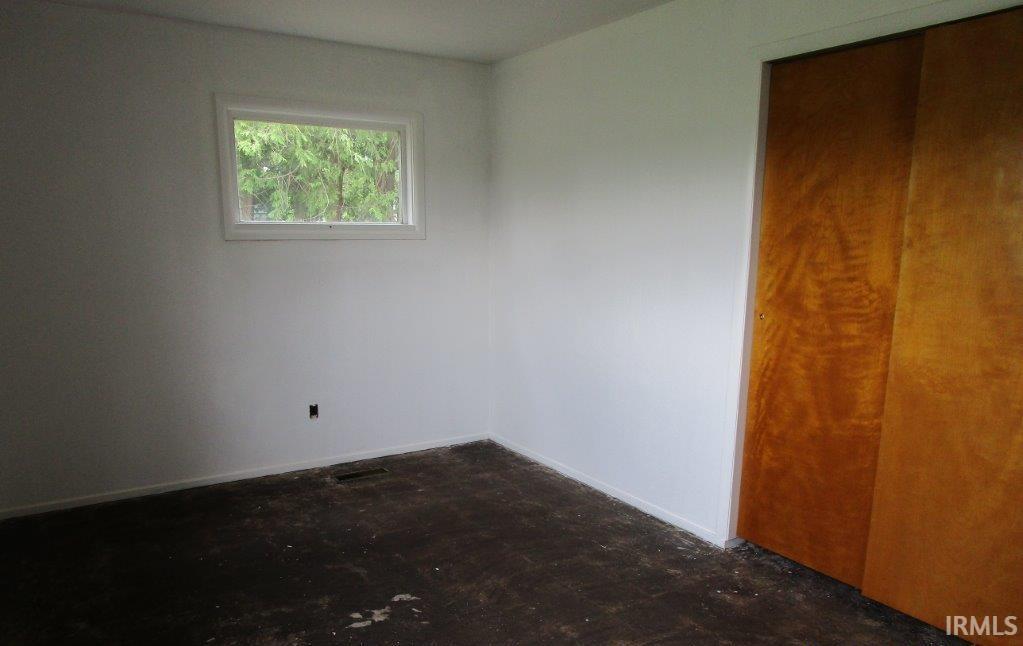Room featuring white walls, a single window, and a built-in closet with wood-finish sliding doors
