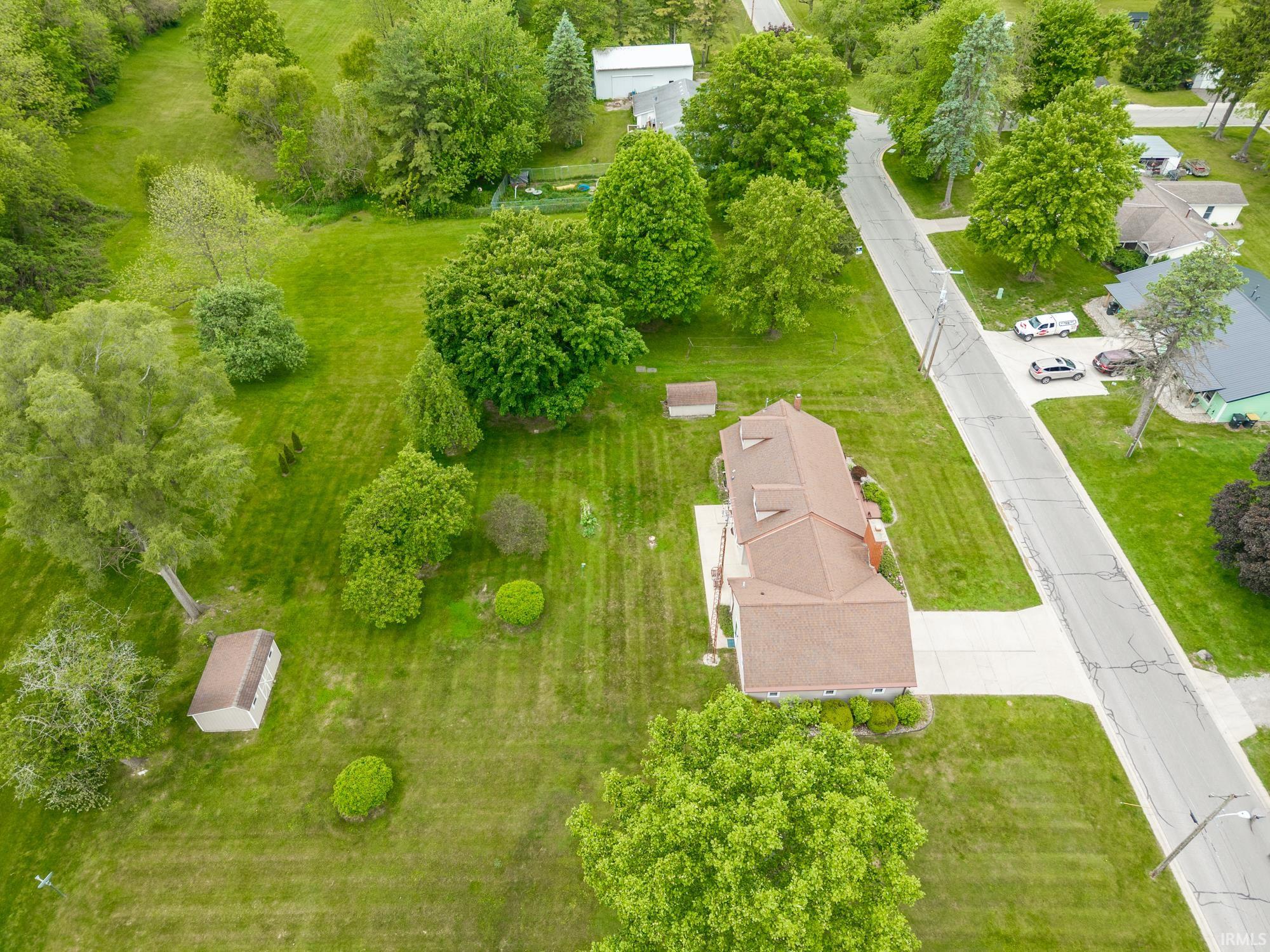 Expansive property showcasing a tan shingled roof, a paved driveway, and established green landscaping