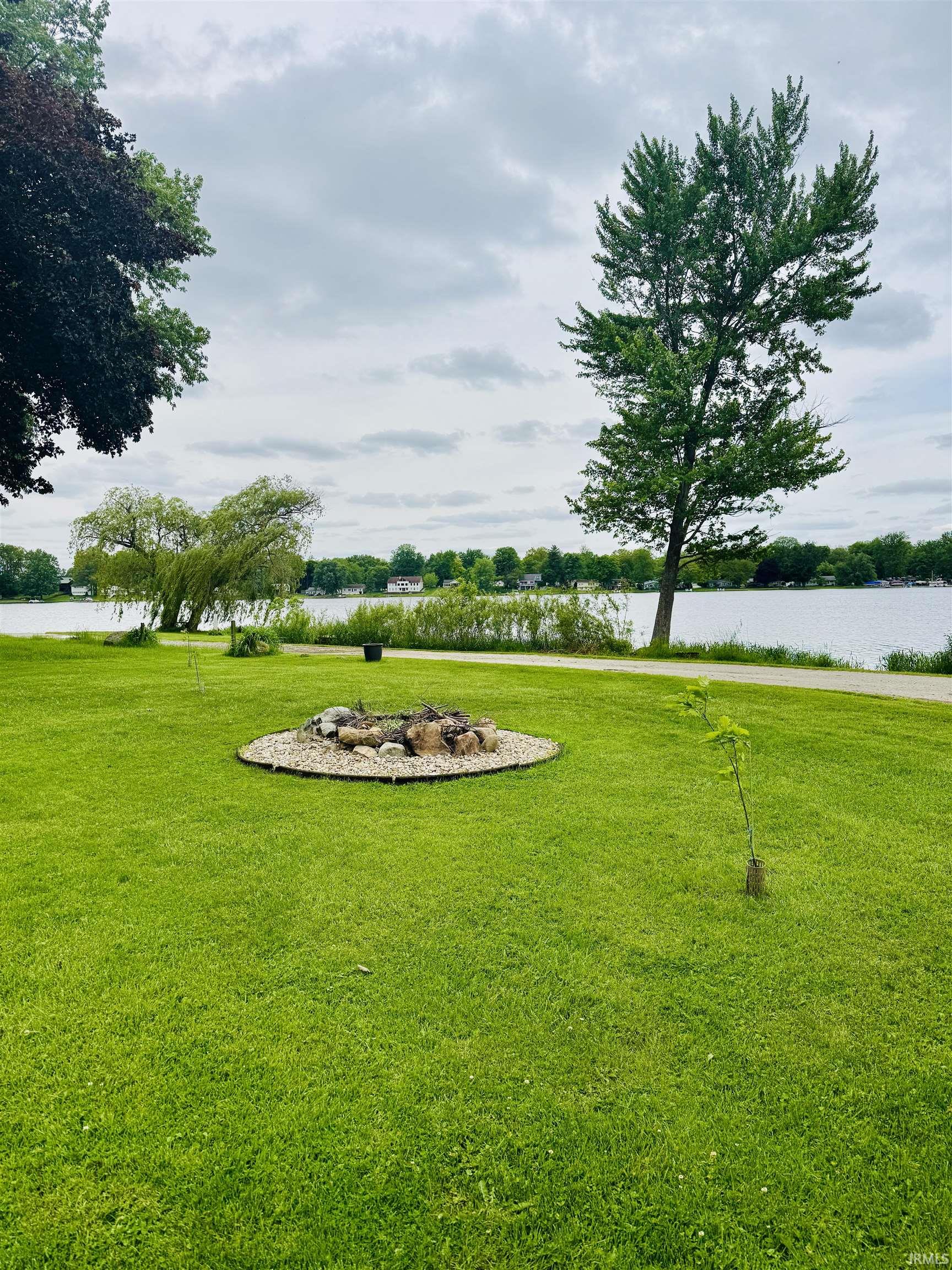 Expansive lawn area featuring a circular stone and gravel fire pit