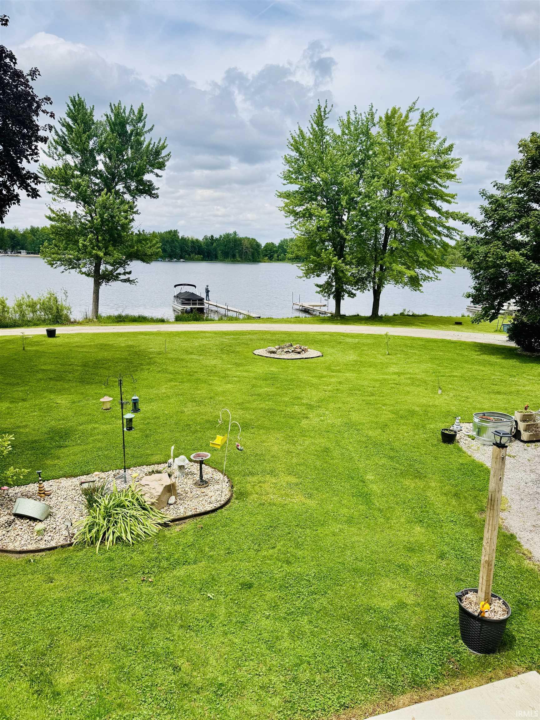 Expansive green lawn with mature trees and a dedicated fire pit area
