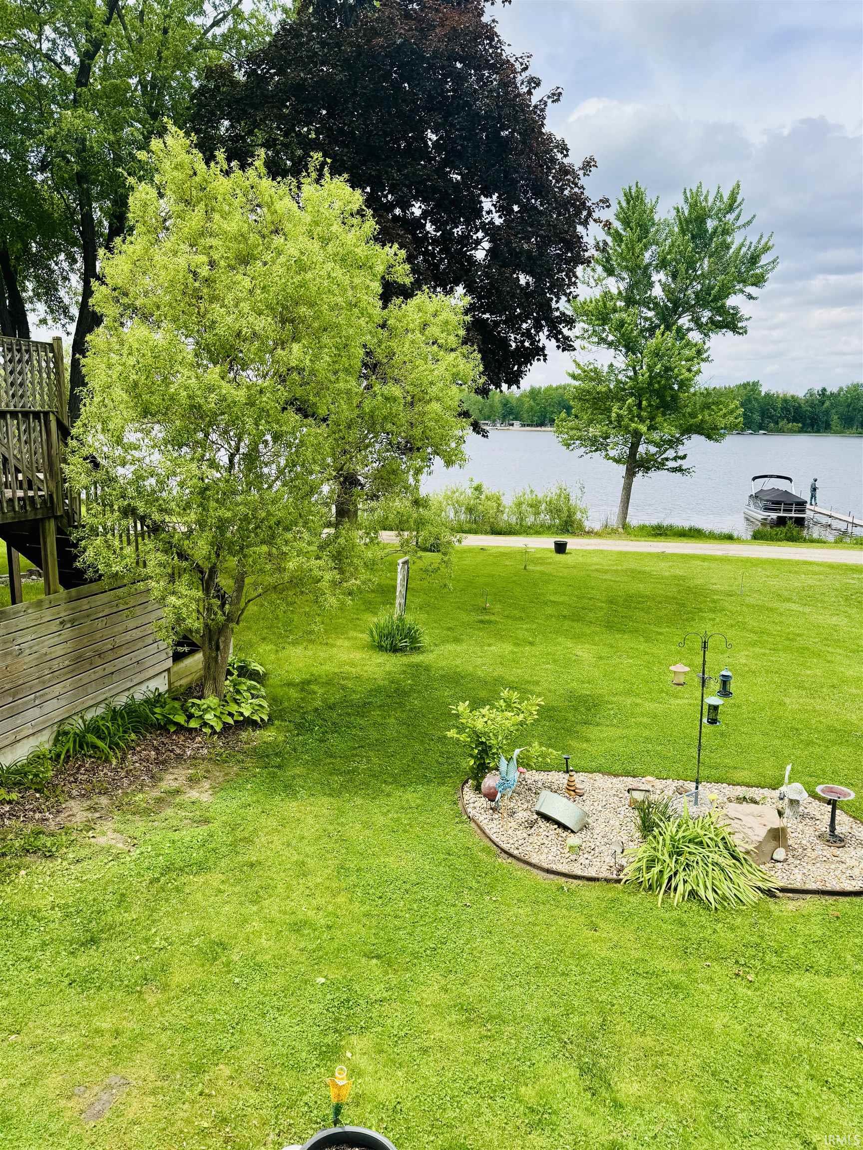Expansive green lawn with mature trees and a distant lakefront