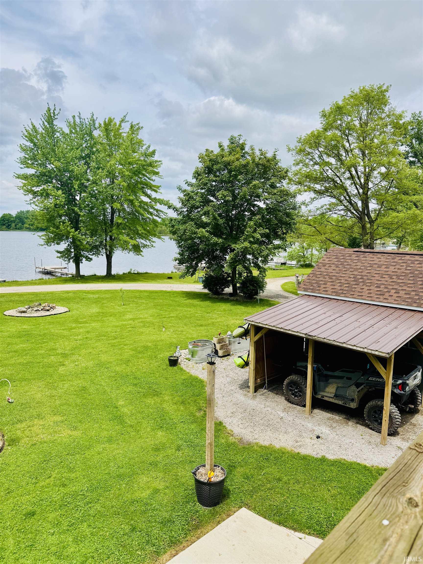 Expansive green lawn with a fire pit area, featuring a lakefront setting with a private dock