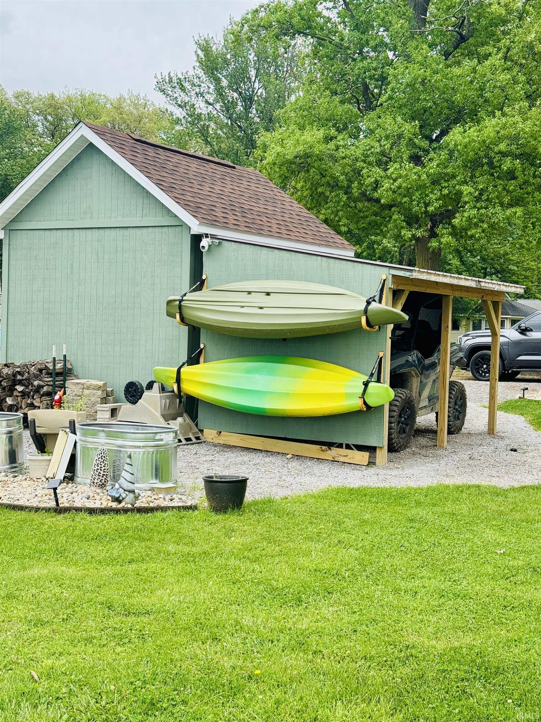 Gable-roof storage shed with light green vertical siding and shingle roofing