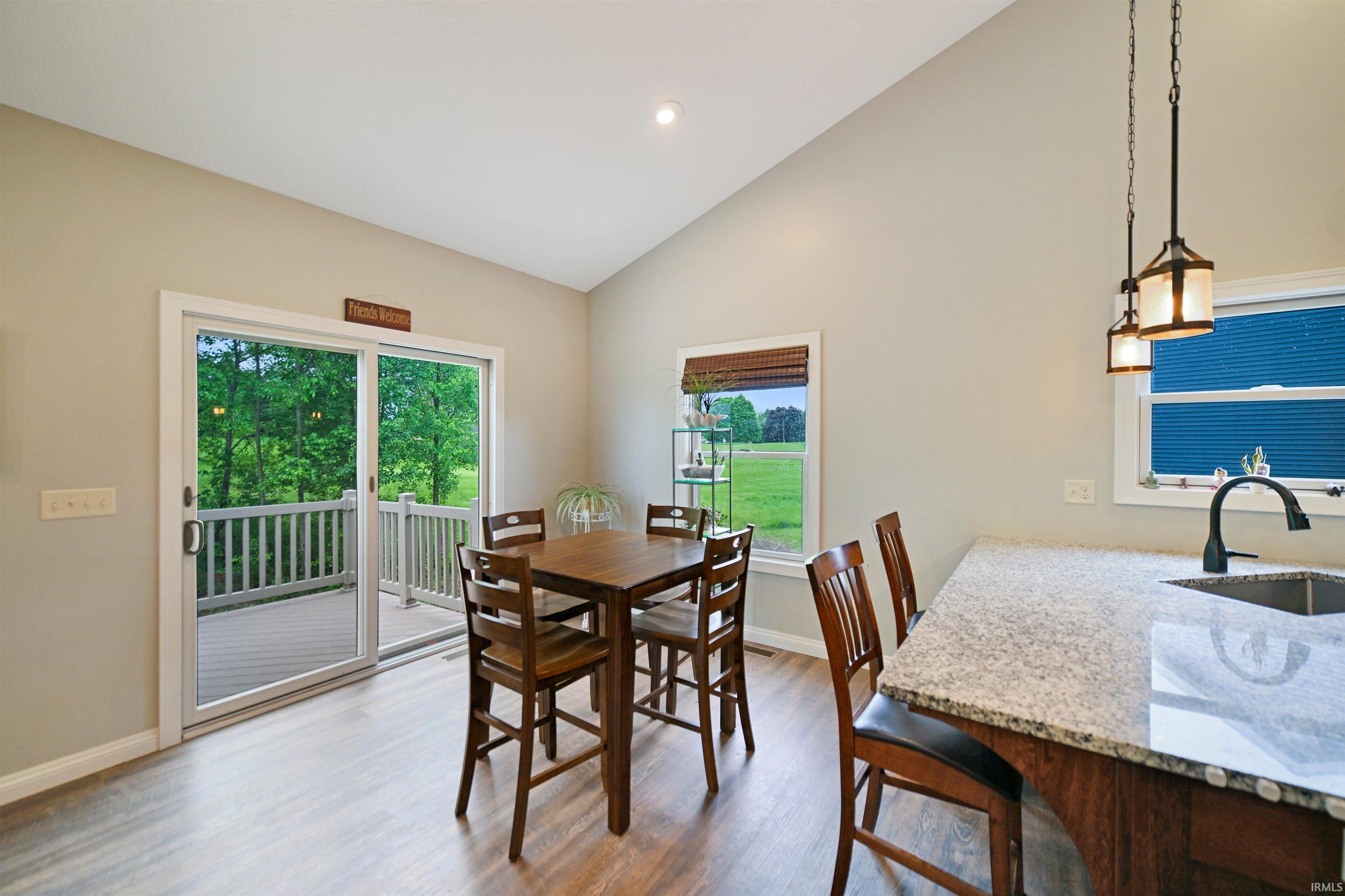 Bright kitchen area featuring wood-finish flooring, a vaulted ceiling, and a sliding glass door leading to a deck