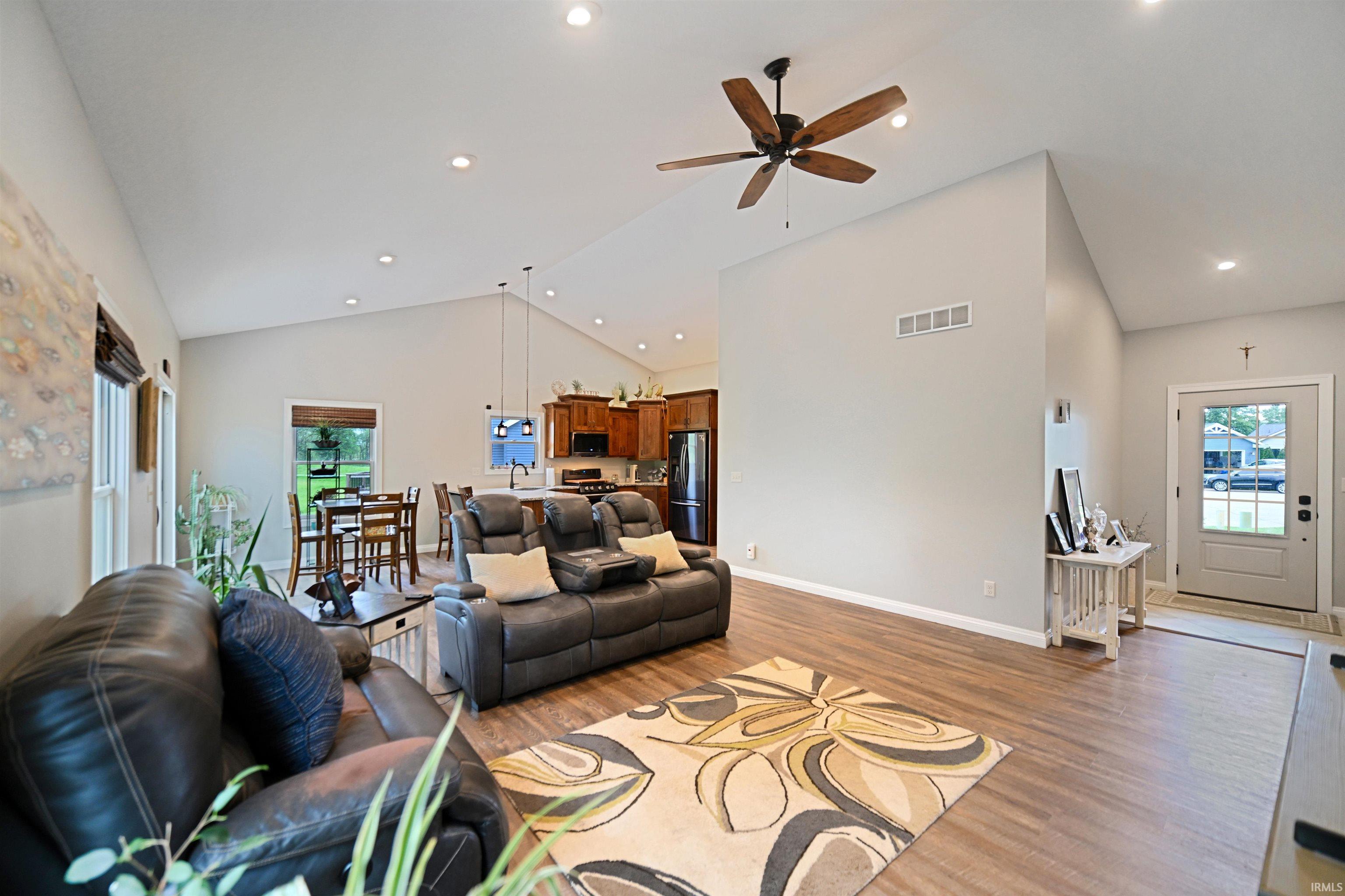 Open-concept living area with vaulted ceilings, wood-finish flooring, recessed lighting, and a ceiling fan