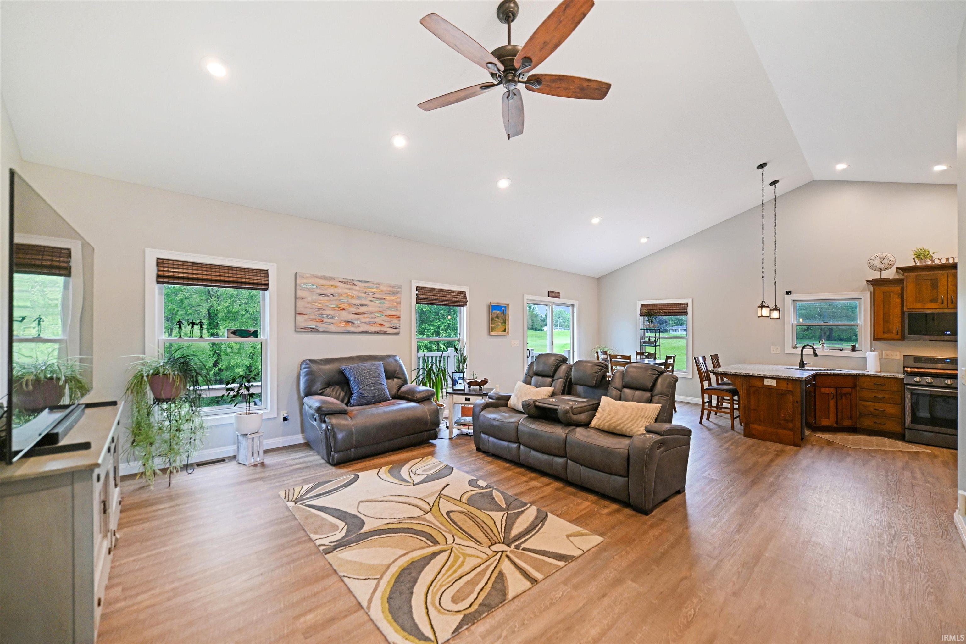 Open-concept living space with a vaulted ceiling, wood-finish flooring, recessed lighting, and a ceiling fan