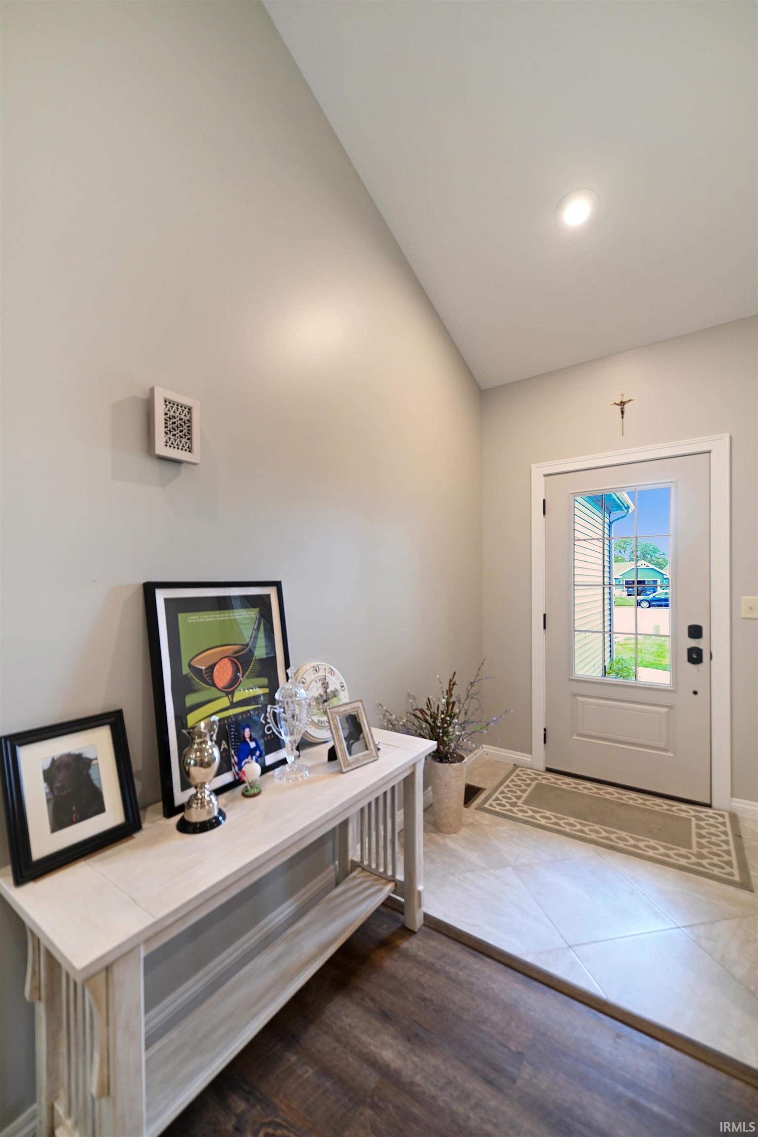 Vaulted ceiling entry foyer featuring a light-colored door with integrated window, recessed lighting, wood-finish flooring, and light-toned wall paint