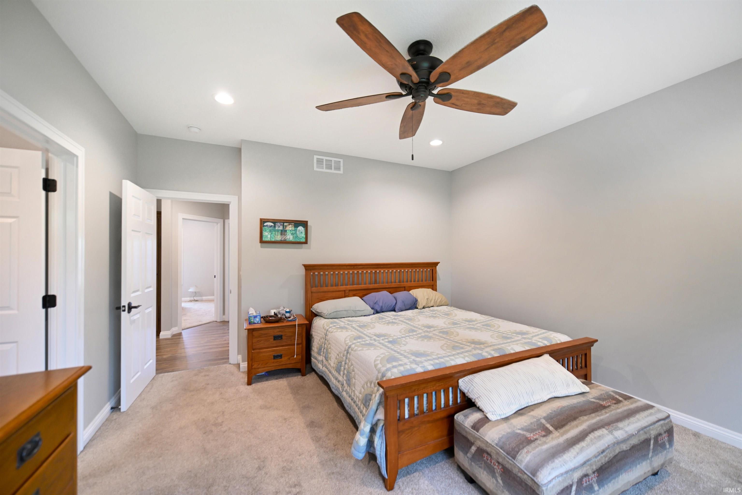 Carpeted room featuring a ceiling fan with wood-finish blades, recessed lighting, and a white six-panel door