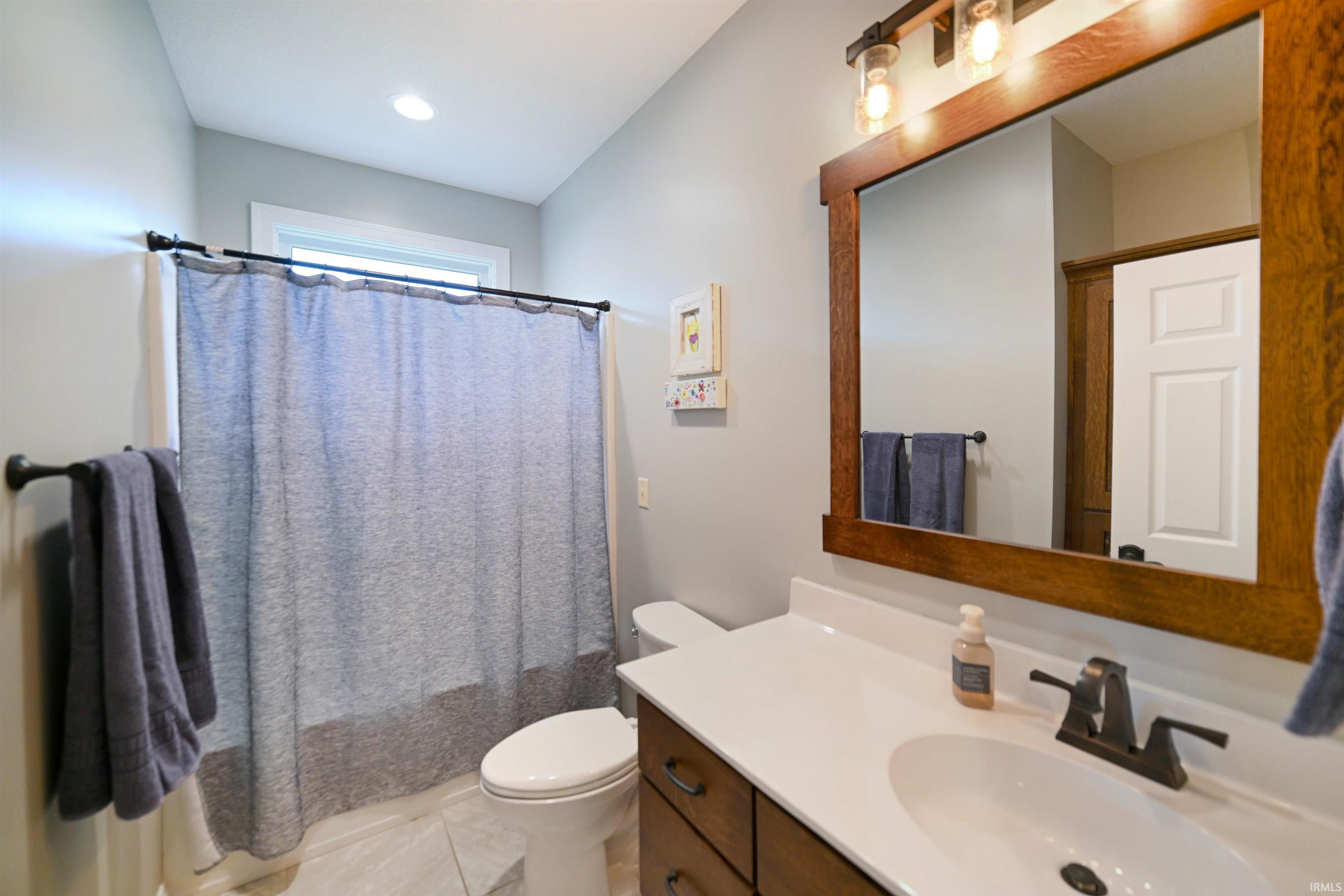 Bathroom featuring a white vanity with an integrated sink, dark bronze faucet, and a large framed mirror with industrial-style lighting