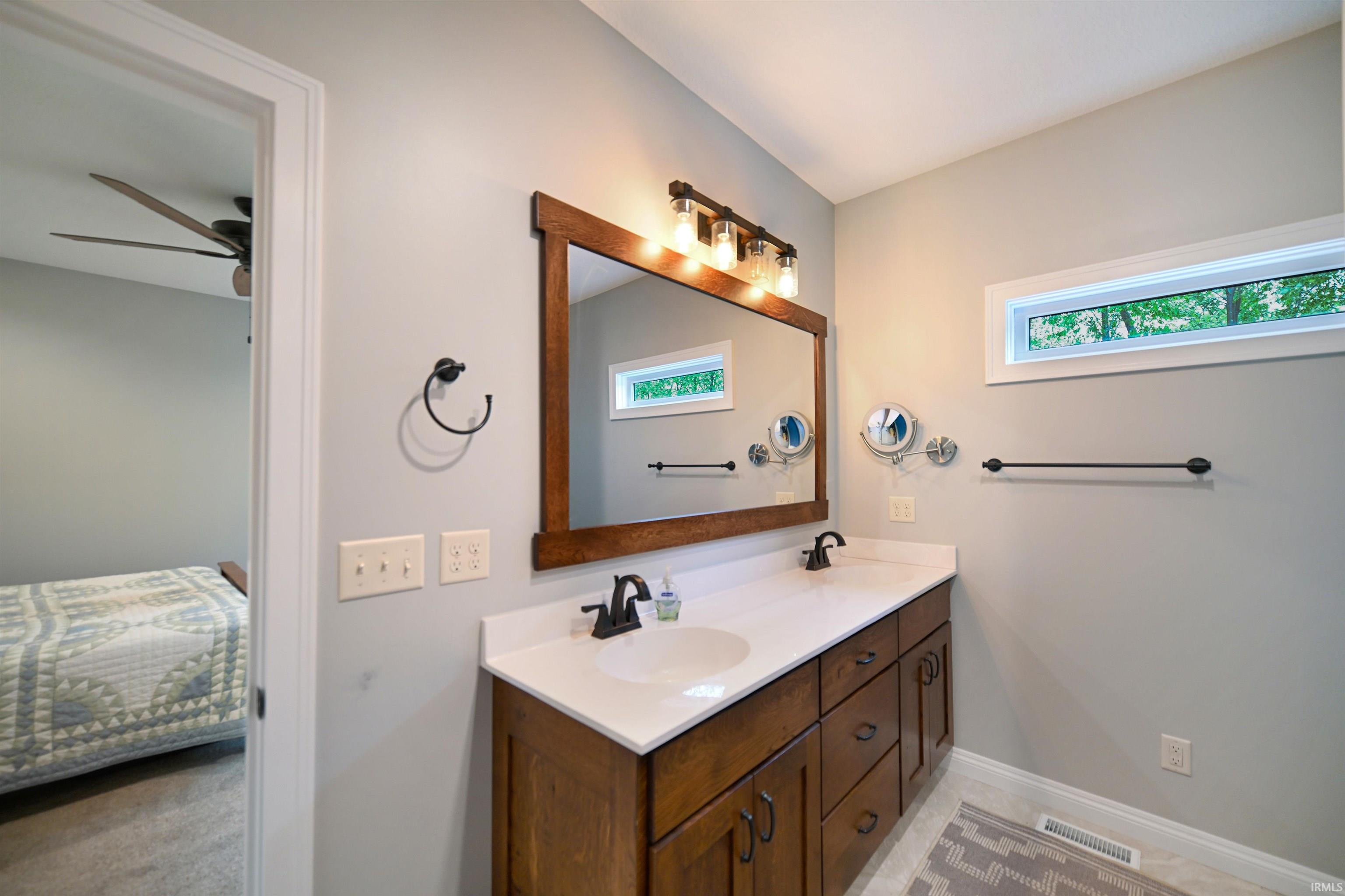 Bathroom featuring a double vanity with wood cabinetry, white countertops, and dual undermount sinks
