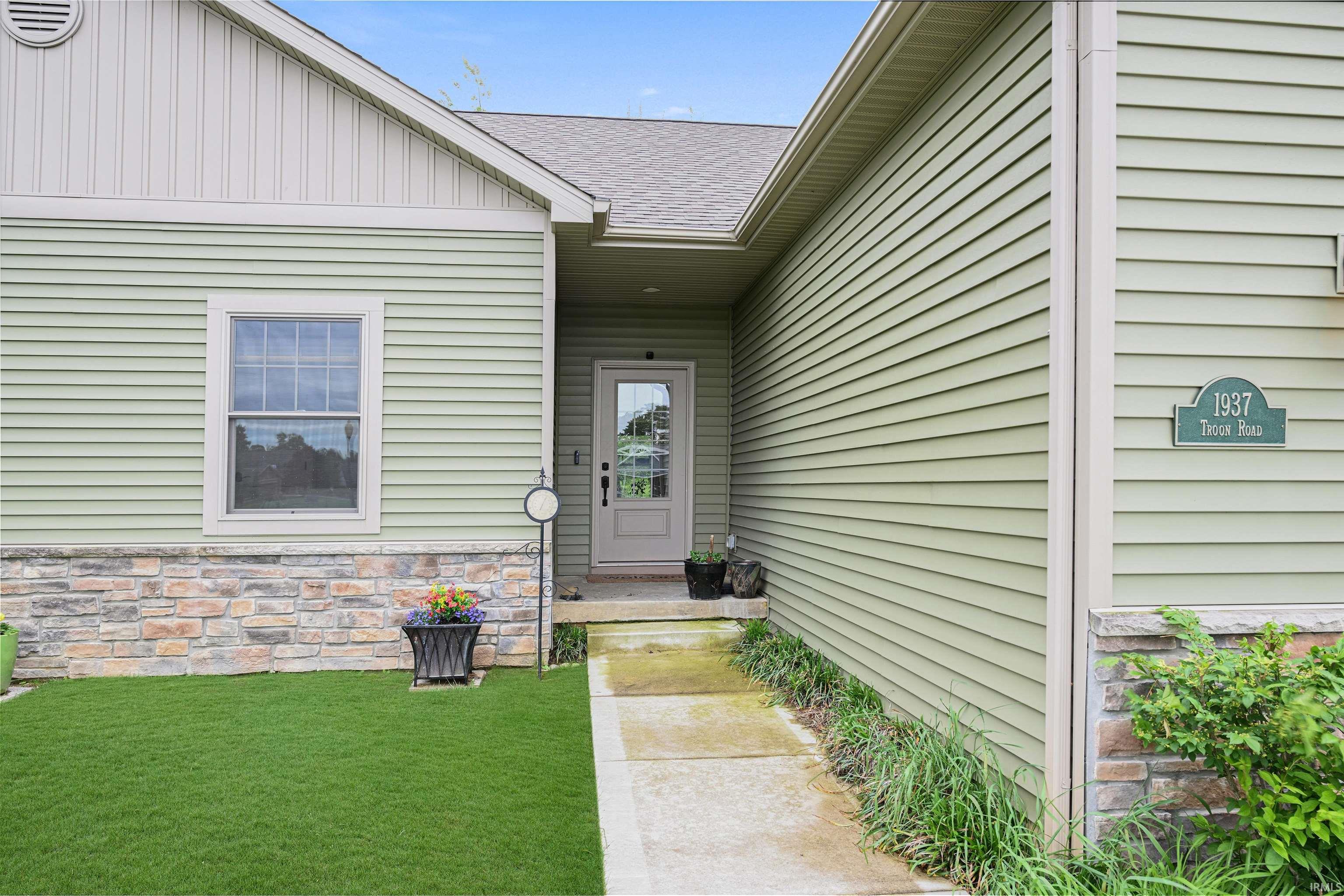 Front exterior featuring light green siding and stone veneer accents