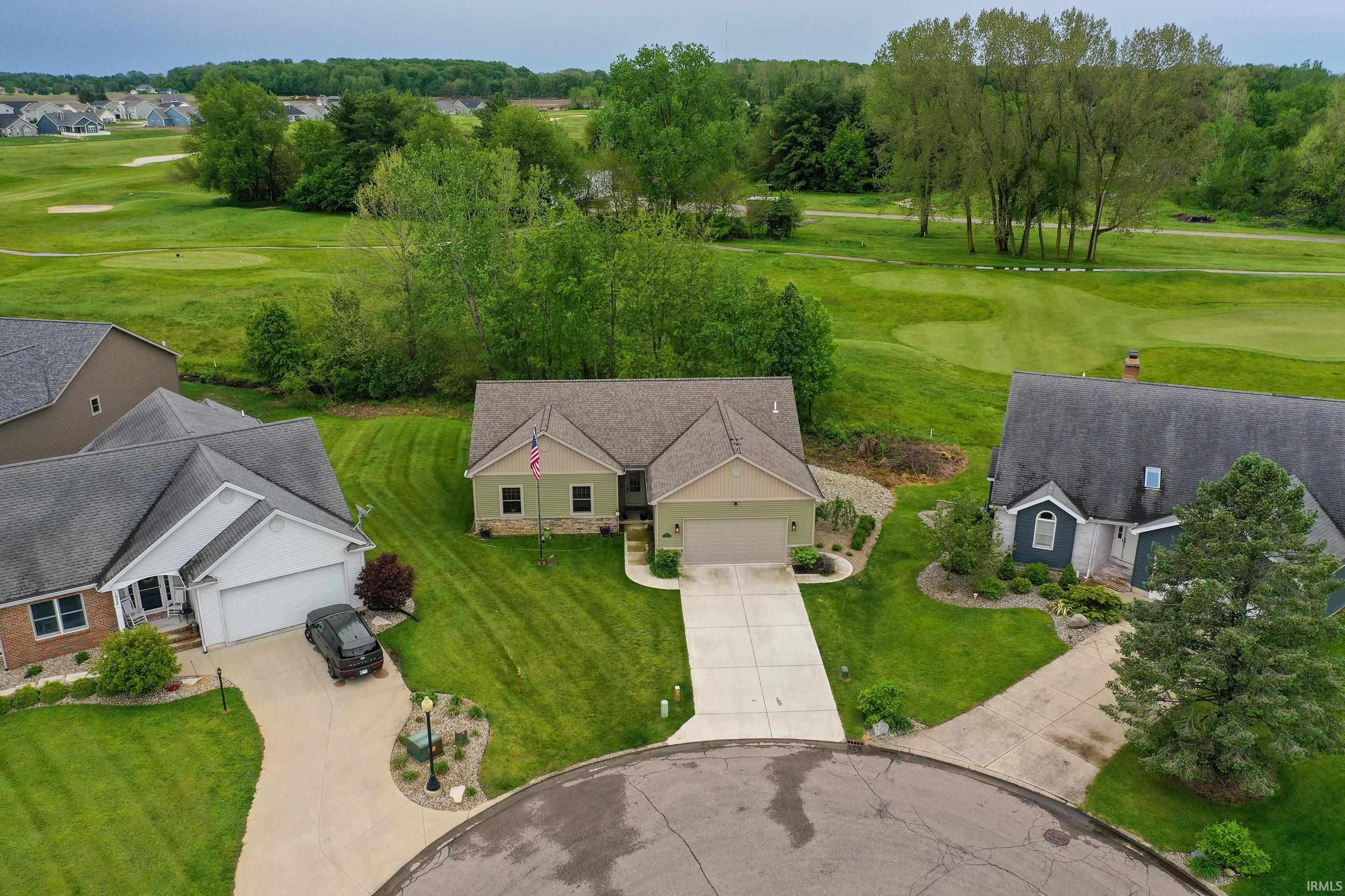 Ranch-style residence featuring a prominent front-facing garage and an expansive green lawn