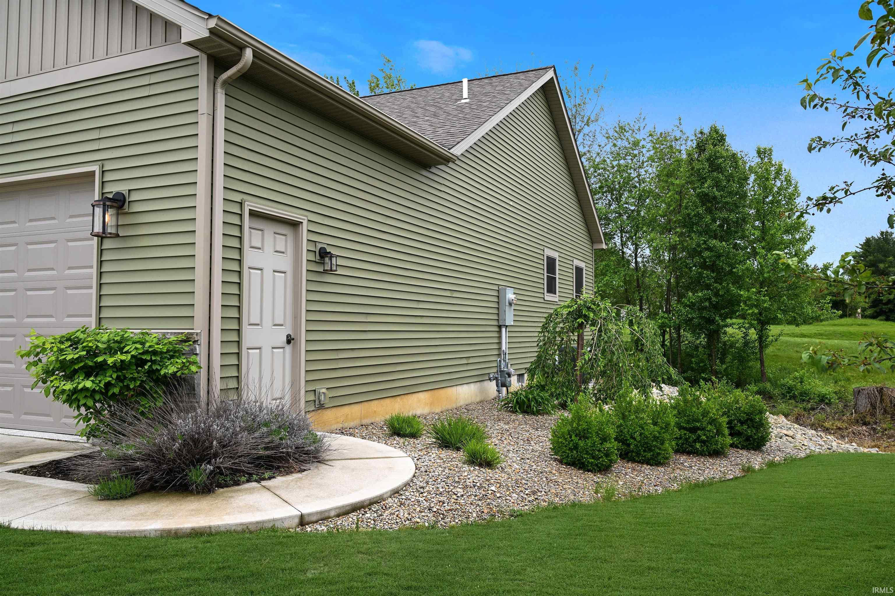 Exterior featuring green horizontal siding, a gray garage door, and a dedicated service door