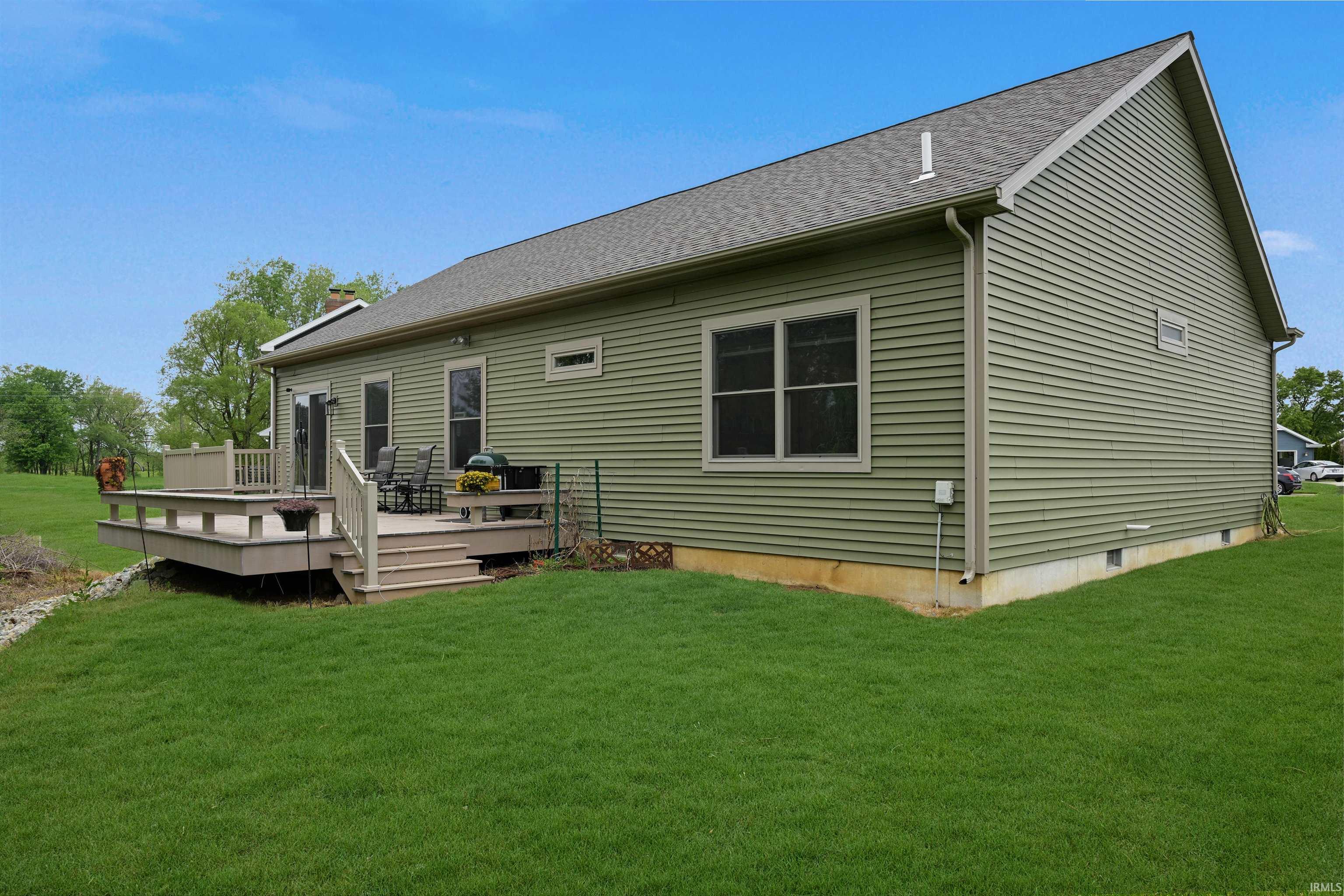 Rear exterior featuring a multi-level wood deck with railings, green siding, a sliding glass door, and a shingled roof