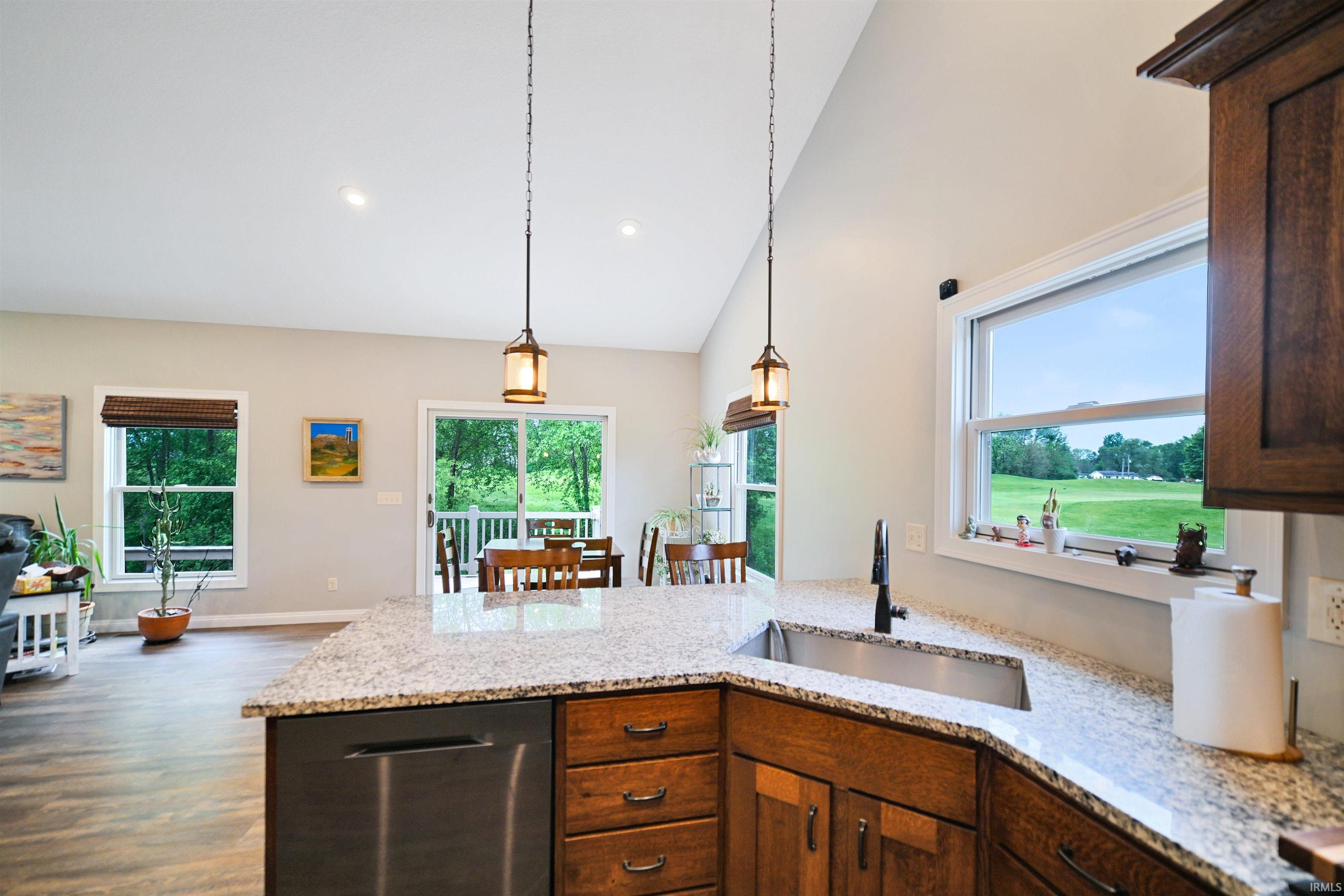 Kitchen island featuring a stainless steel undermount sink, granite countertop, and dark wood cabinetry