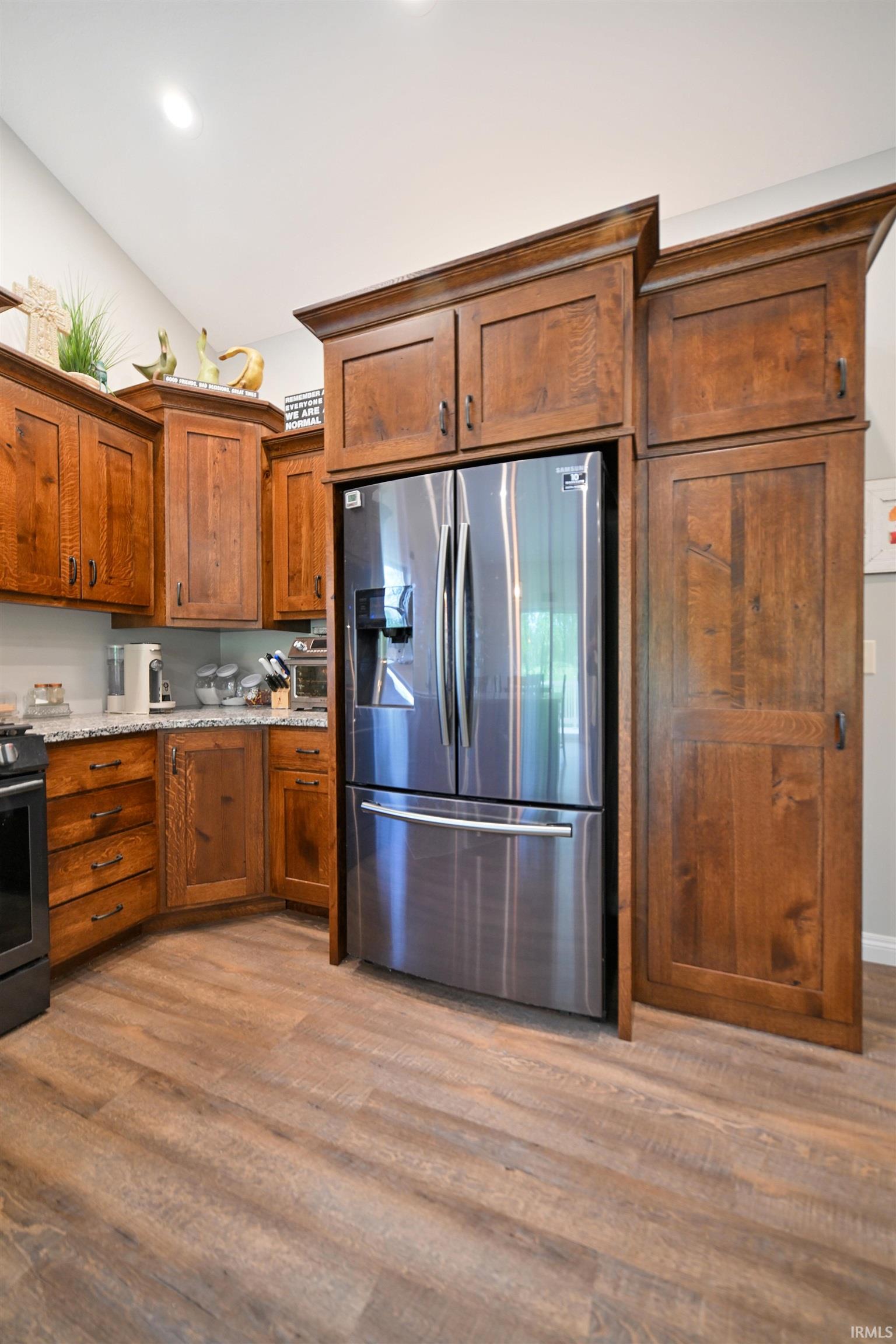 Kitchen featuring wood-finish flooring, custom wood cabinetry, and speckled countertops