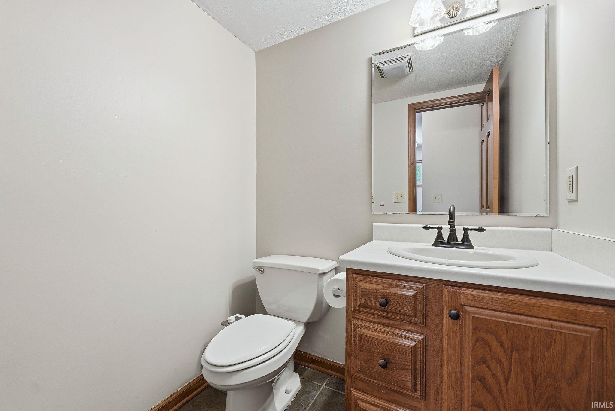 Bathroom featuring a single vanity with wood cabinetry, a white countertop, and an undermount sink