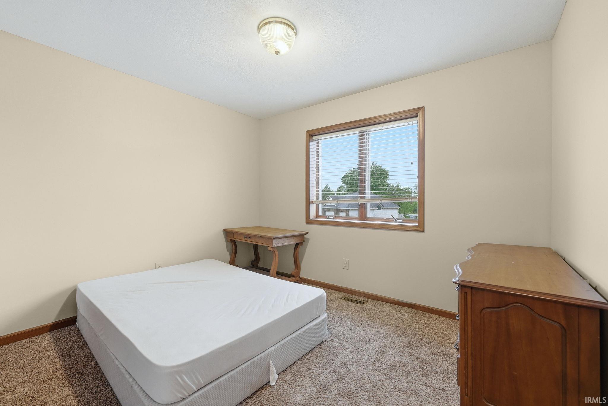 Carpeted room with a double-paned window featuring blinds and dark wood trim