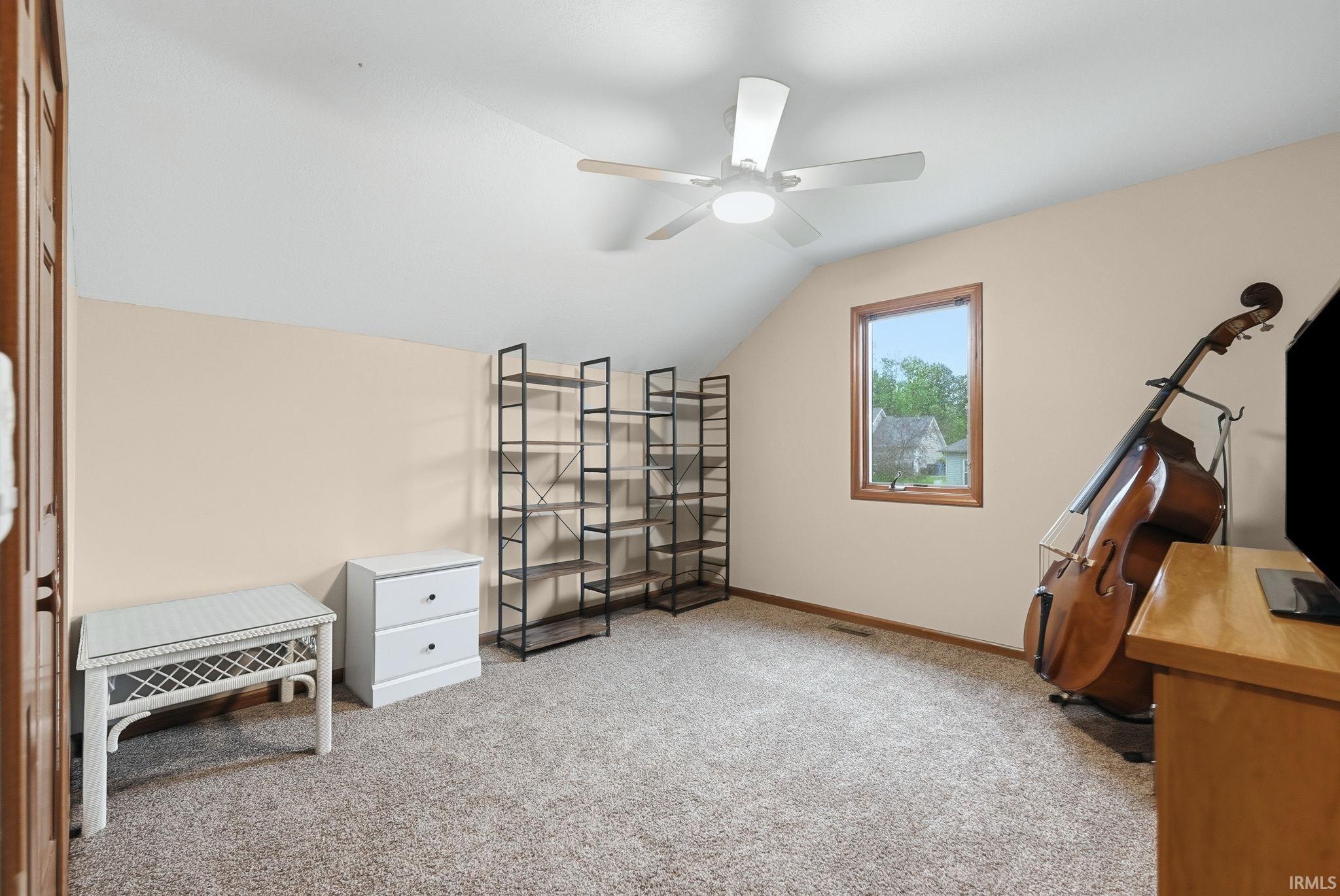 Carpeted room with a pitched ceiling and a ceiling fan