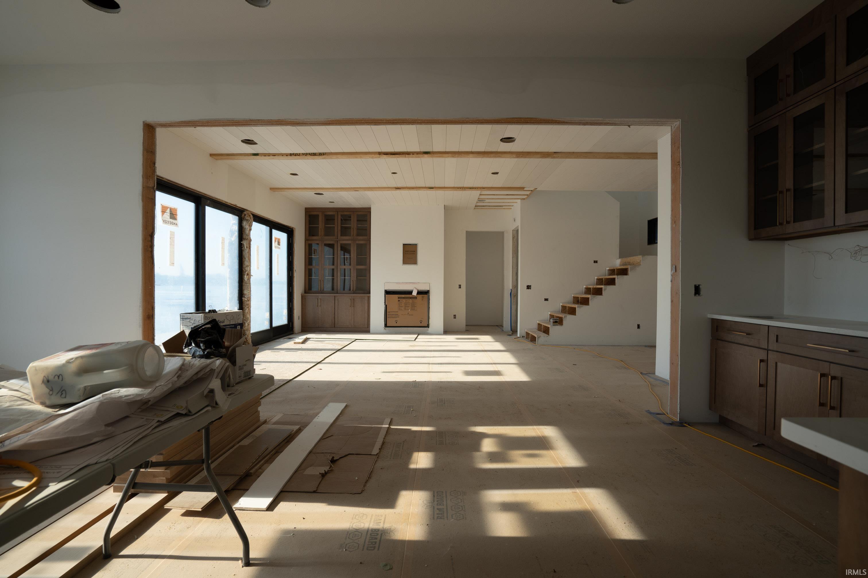 Open-concept interior featuring light-toned walls, recessed lighting, and exposed ceiling beams
