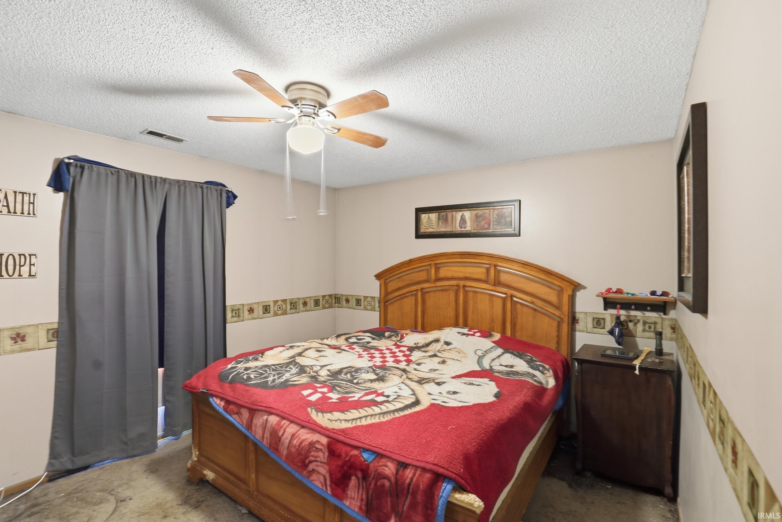 Bedroom featuring a ceiling fan, window with dark curtains, and light-toned walls with a decorative border