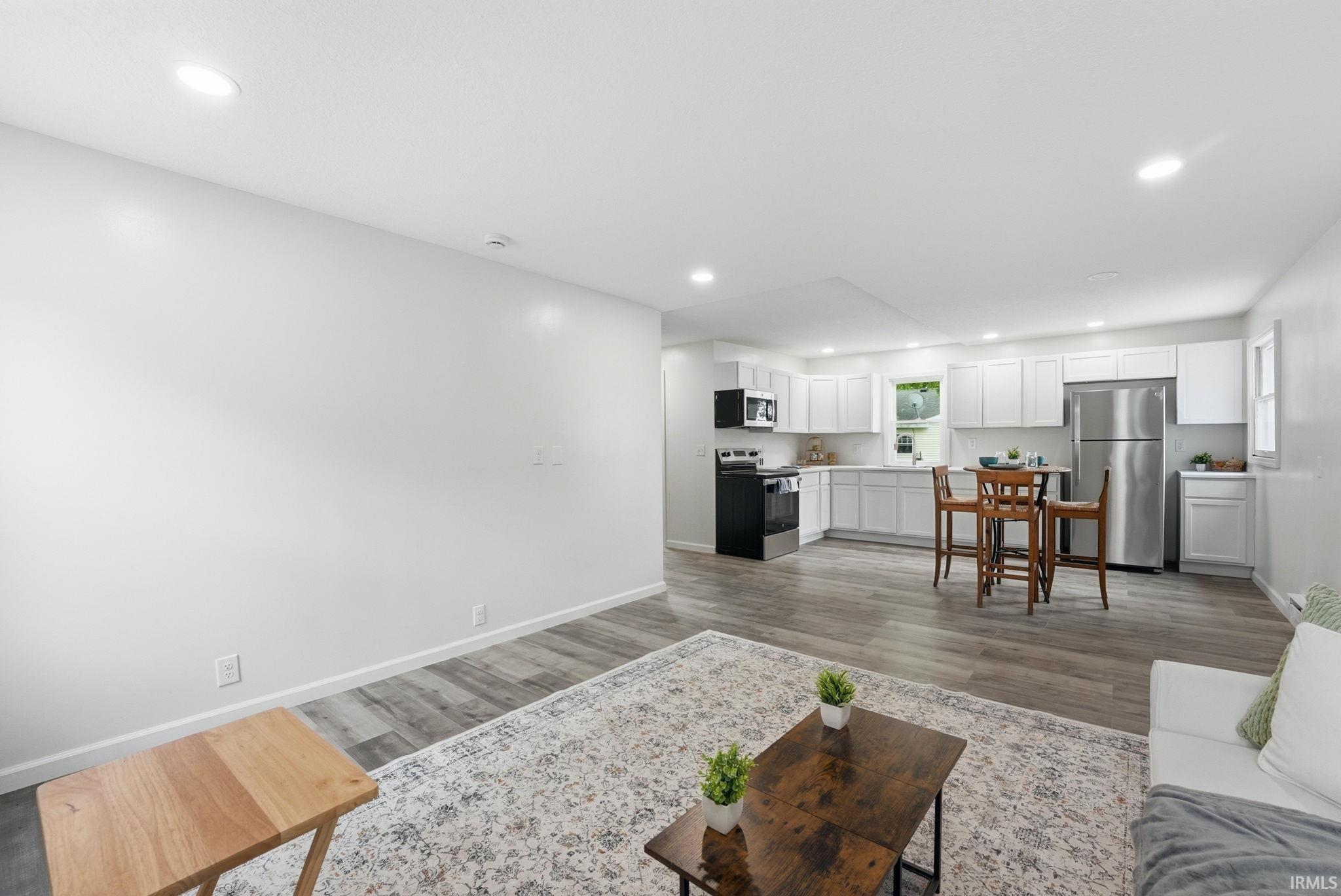 Open-concept living space featuring wood-finish flooring, recessed lighting, and a white color palette