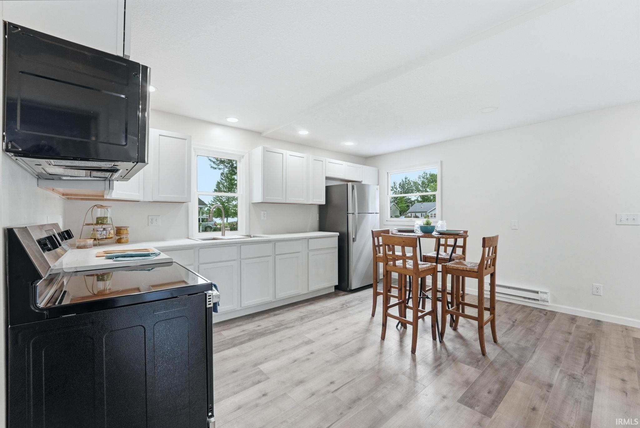 Kitchen featuring white shaker-style cabinetry, light-toned countertops, and wood-finish flooring