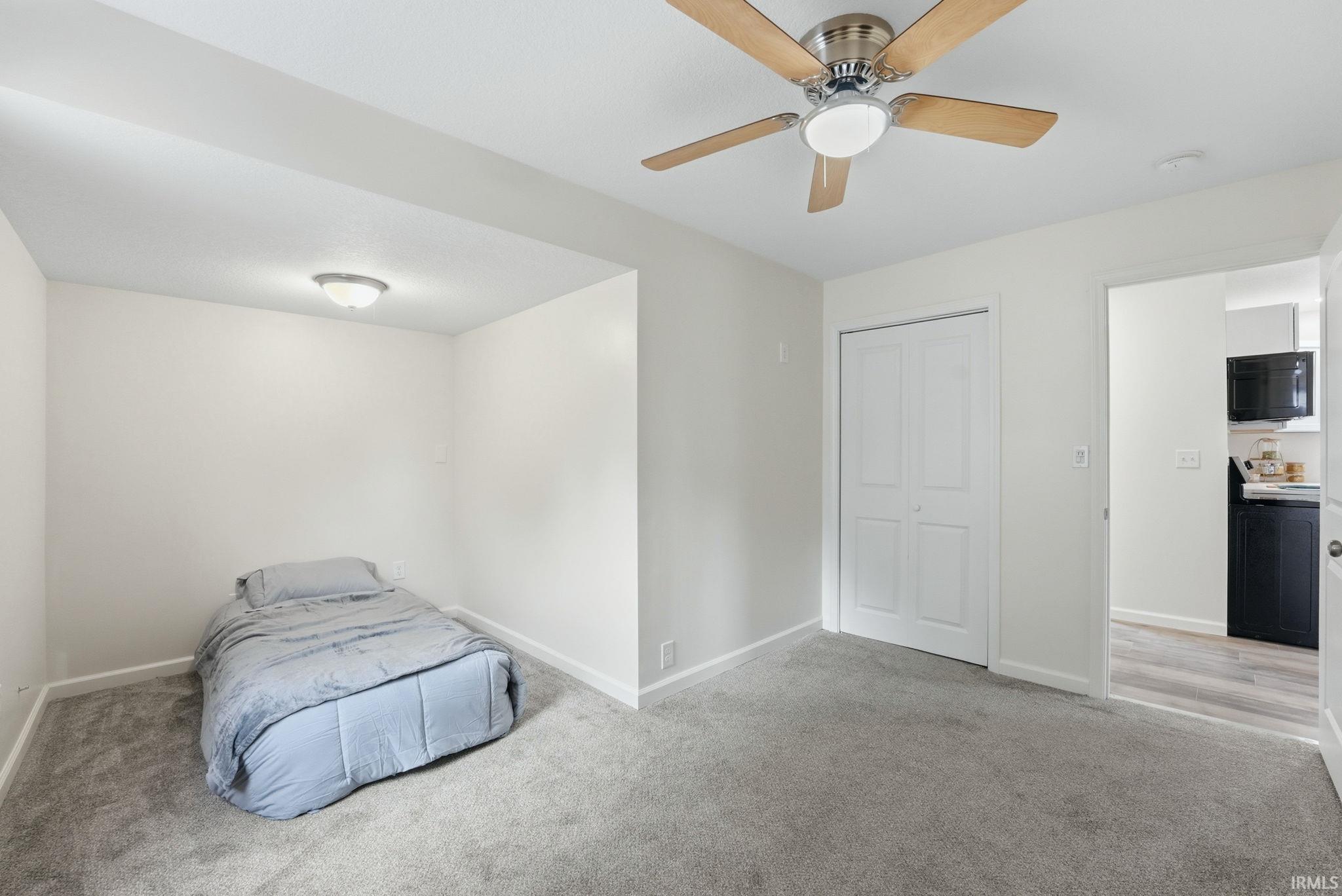 Carpeted interior space featuring a ceiling fan with integrated lighting, bi-fold closet doors, and light-toned walls