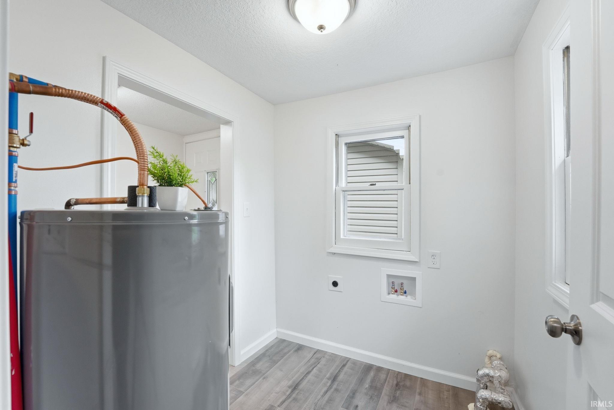 Utility space with wood-finish flooring, white walls, and baseboards