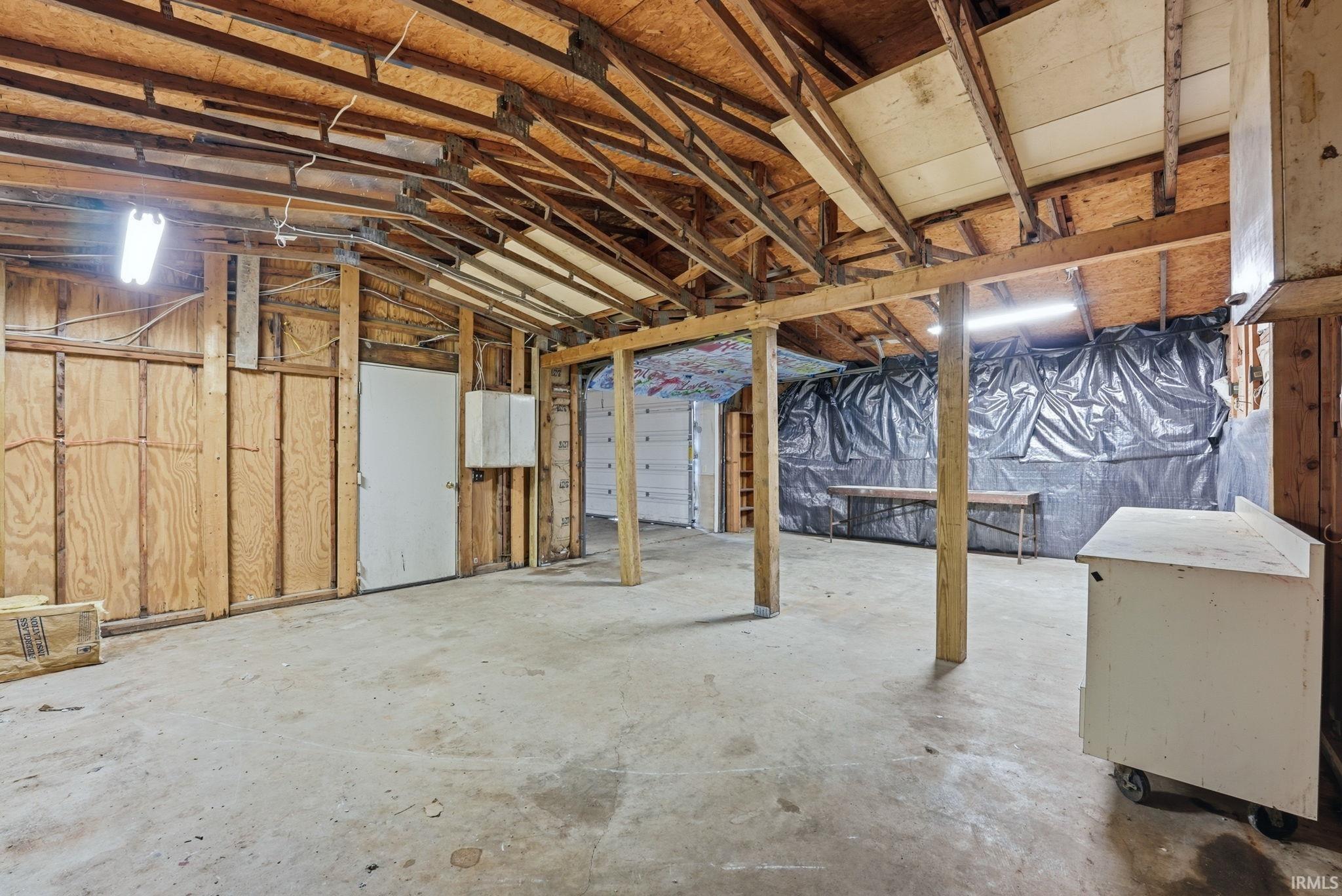 Spacious unfinished interior featuring exposed wooden ceiling rafters and structural beams